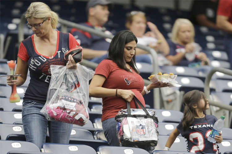 With their belongings in clear plastic bags, fans arrive before a preseason game, Aug. 25, 2013, in Houston. (AP/Eric Gay)