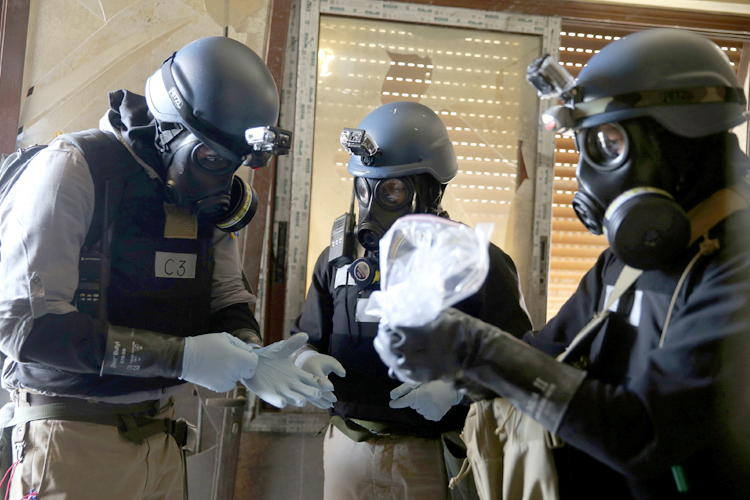 A U.N. chemical weapons expert, wearing a gas mask, holds a plastic bag containing samples from one of the sites of an alleged chemical weapons attack in the Ain Tarma neighbourhood of Damascus August 29, 2013. (Mohamed Abdullah/Reuters)