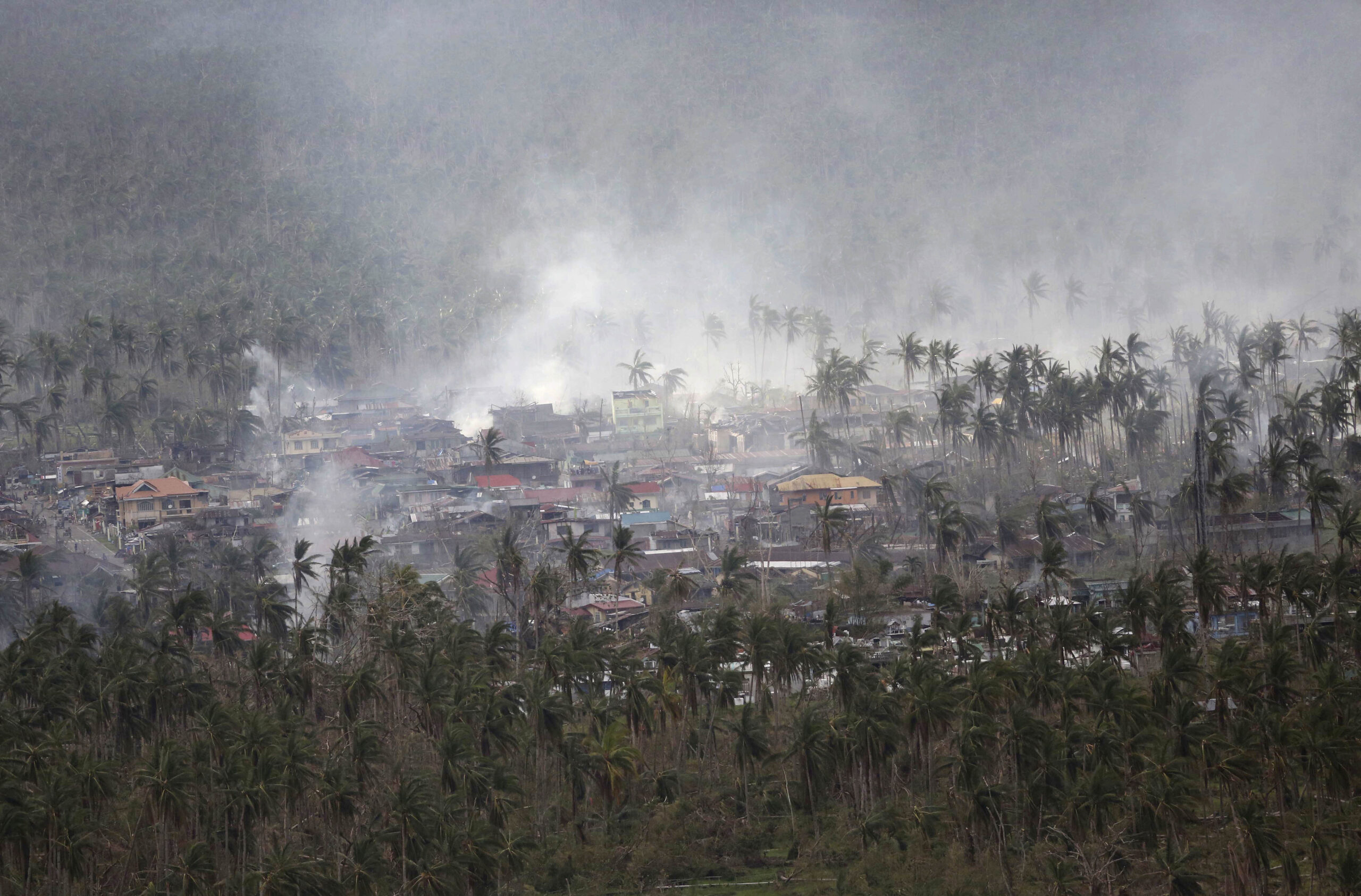 Smoke billows around damaged houses in this aerial shot from a Philippine Air Force helicopter at typhoon-ravaged Leyte province, central Philippines Monday, Nov. 18, 2013. When a newspaper for Filipino workers in New Zealand told readers how to donate to the typhoon relief effort in their homeland, it mentioned agencies like the Red Cross but not a list of government bank accounts that the Philippine Embassy had sent over. (AP Photo/Aaron Favila) (AP/Aaron Favila)