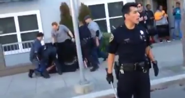 Police hold cyclist on the ground as fellow SFPD officers stand guard (YouTube)