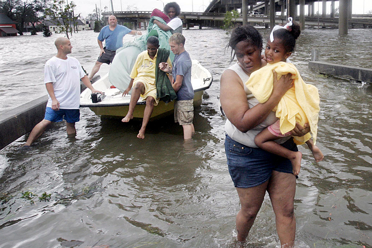 Shante Gruld carries Janeka Garner, 5, to safety after they were rescued from their flooded home by boat in New Orleans, Aug. 29, 2005. (AP/Eric Gay)