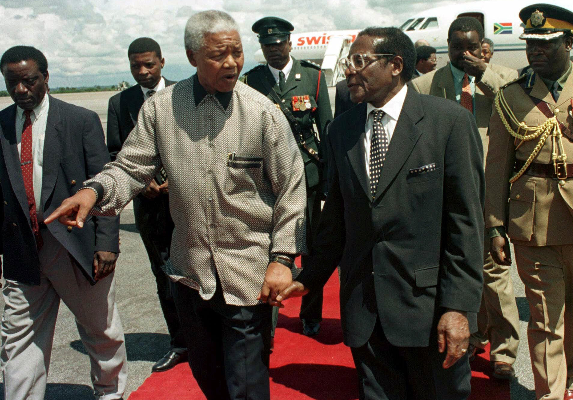 This Sunday Dec. 13, 1998 file photo shows former South African president Nelson Mandela, left, with Zimbabwean President Robert Mugabe in Harare. (AP/Rob Cooper)