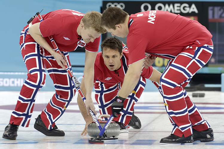 Norway's vice Torger Nergaard delivers a stone as lead, Haavard Vad Petersson, and second, Christoffer Svae, sweep during their men's curling round robin game against Sweden, February 13, 2014. (Reuters/Ints Kalnins)
