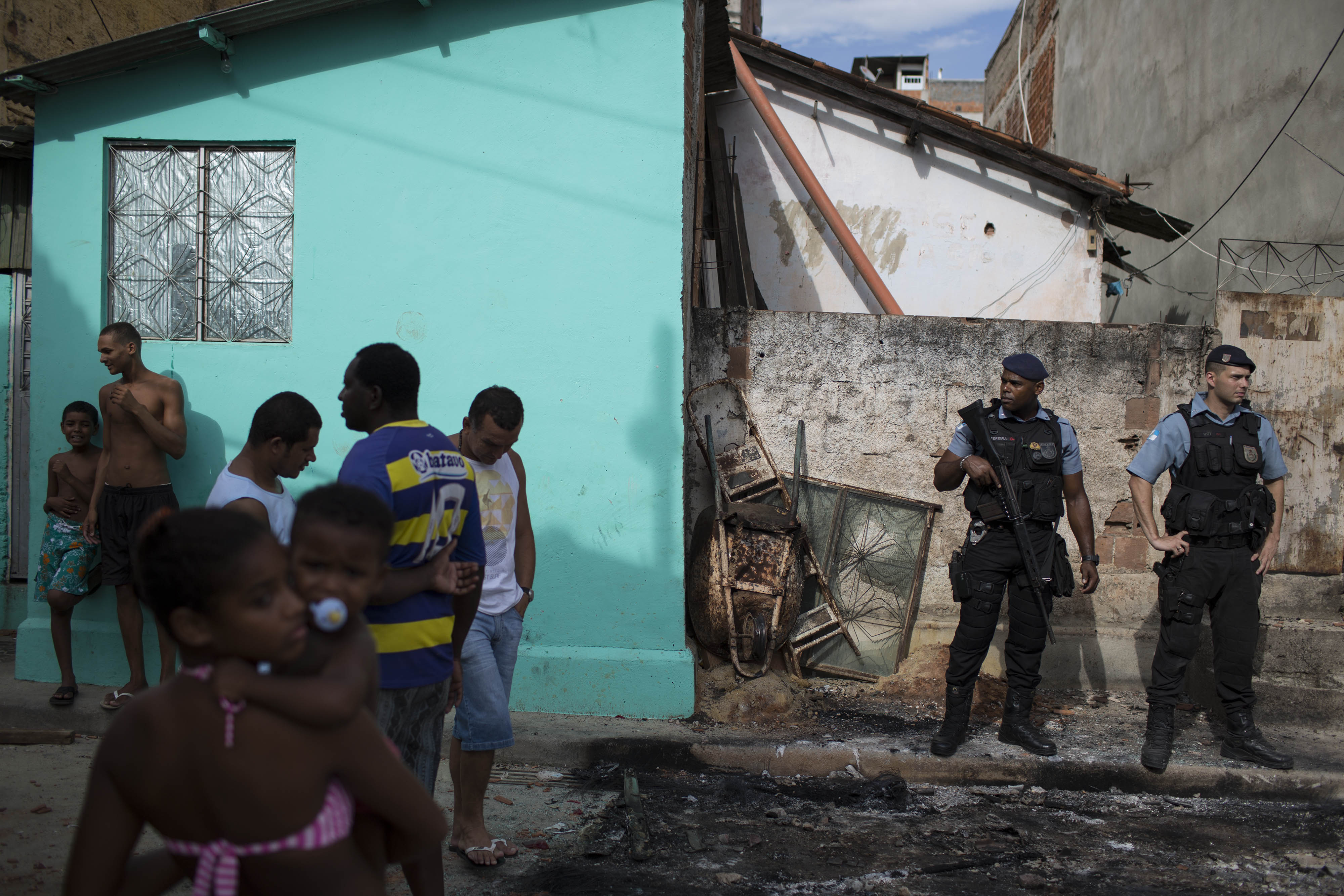 Police officers, right, stand guard among burned remains of a car from the Pacifying Police Unit post (AP)