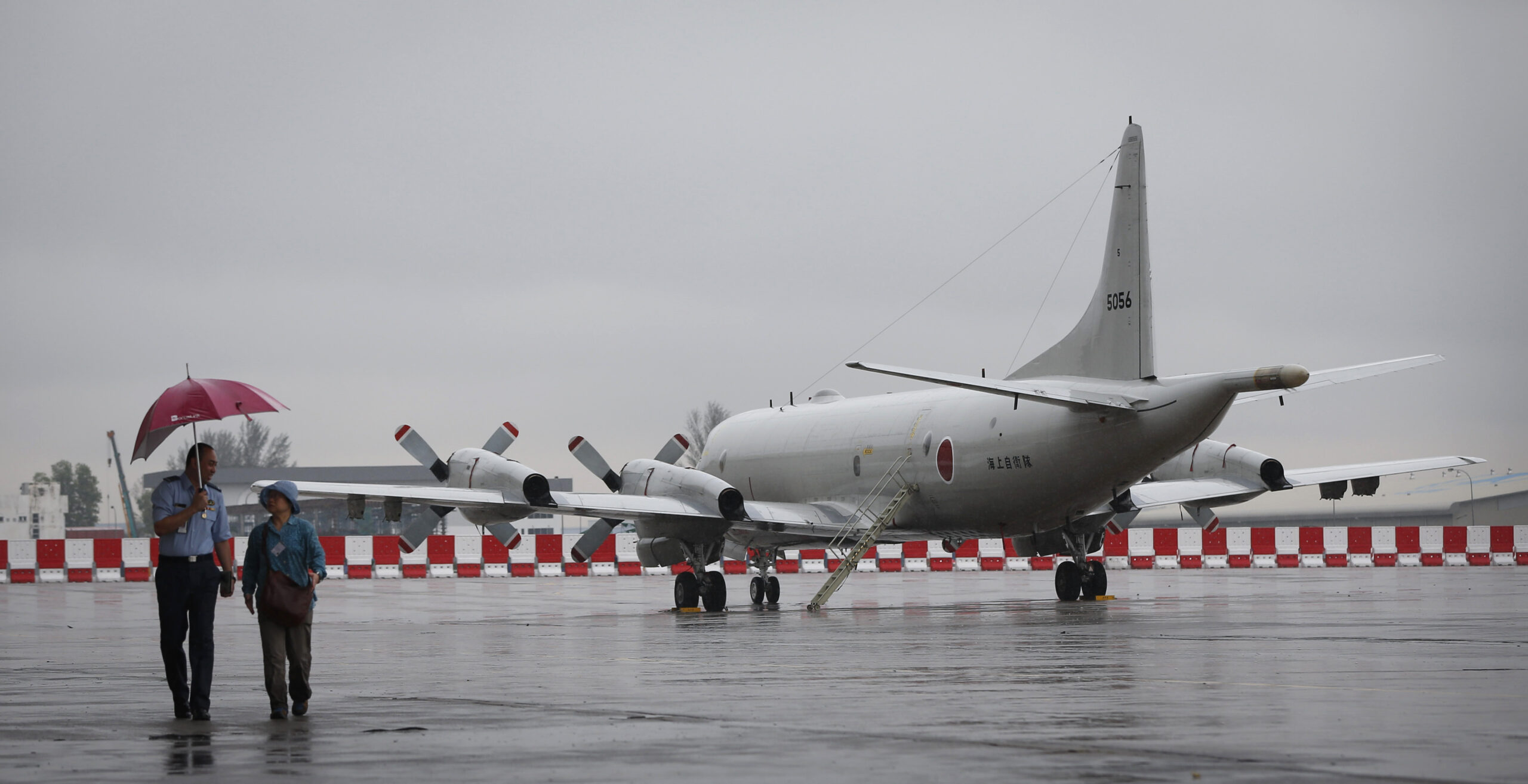 Ground Crew passing by a Japanese Maritime Defence Force P3C plane park at Royal Malaysia Airforce Base in Subang, Malaysia, Tuesday, March 18, 2014. (AP/Vincent Thian)