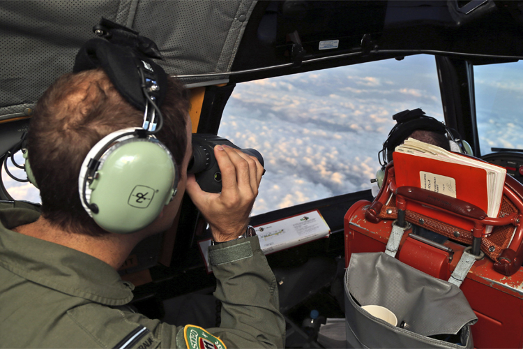 A crew member aboard a Royal Australian Air Force (RAAF) AP-3C Orion uses binoculars as it flies over the southern Indian Ocean during the search for missing Malaysian Airlines flight MH370. (Reuters/Rob Griffith)