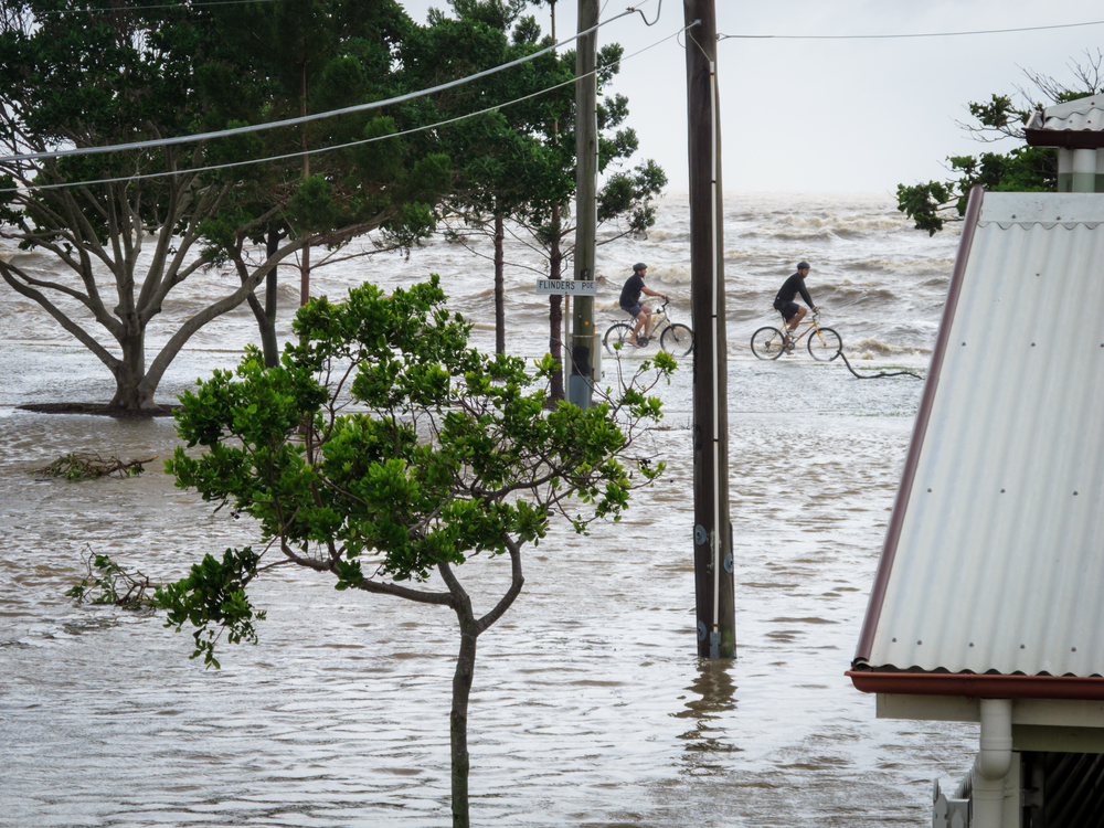 A pair of cyclists ride along the sea wall during the storm surge floods in Brisbane, Australia on January 27, 2013. (Silken Photography/Shutterstock)