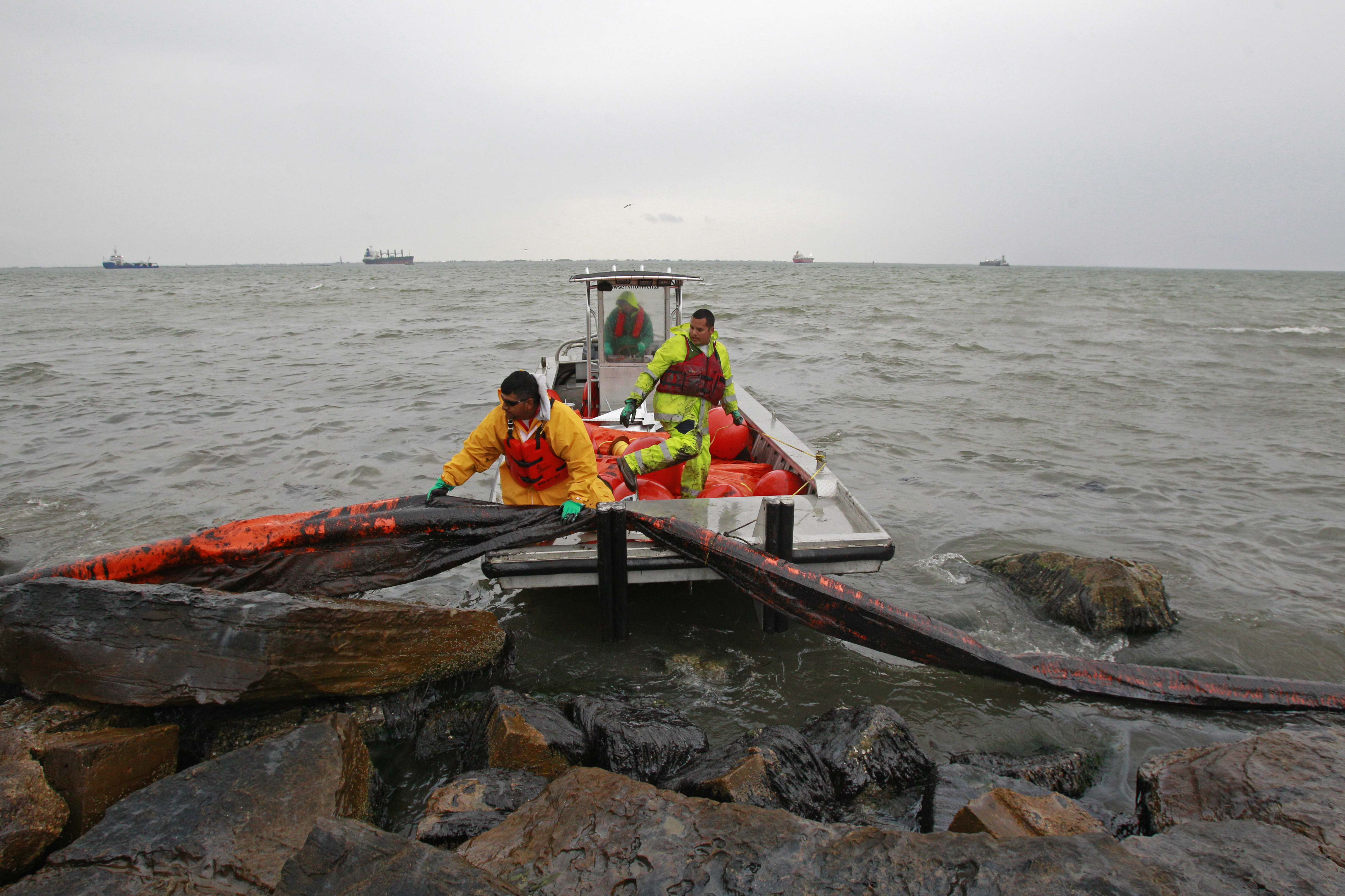 Workers try to move oil containment boom from the shore area along Boddeker Rd. on the Eastern end of Galveston near the ship channel Sunday, March 23, 2014, in Galveston. (AP Photo/Houston Chronicle, Melissa Phillip)
