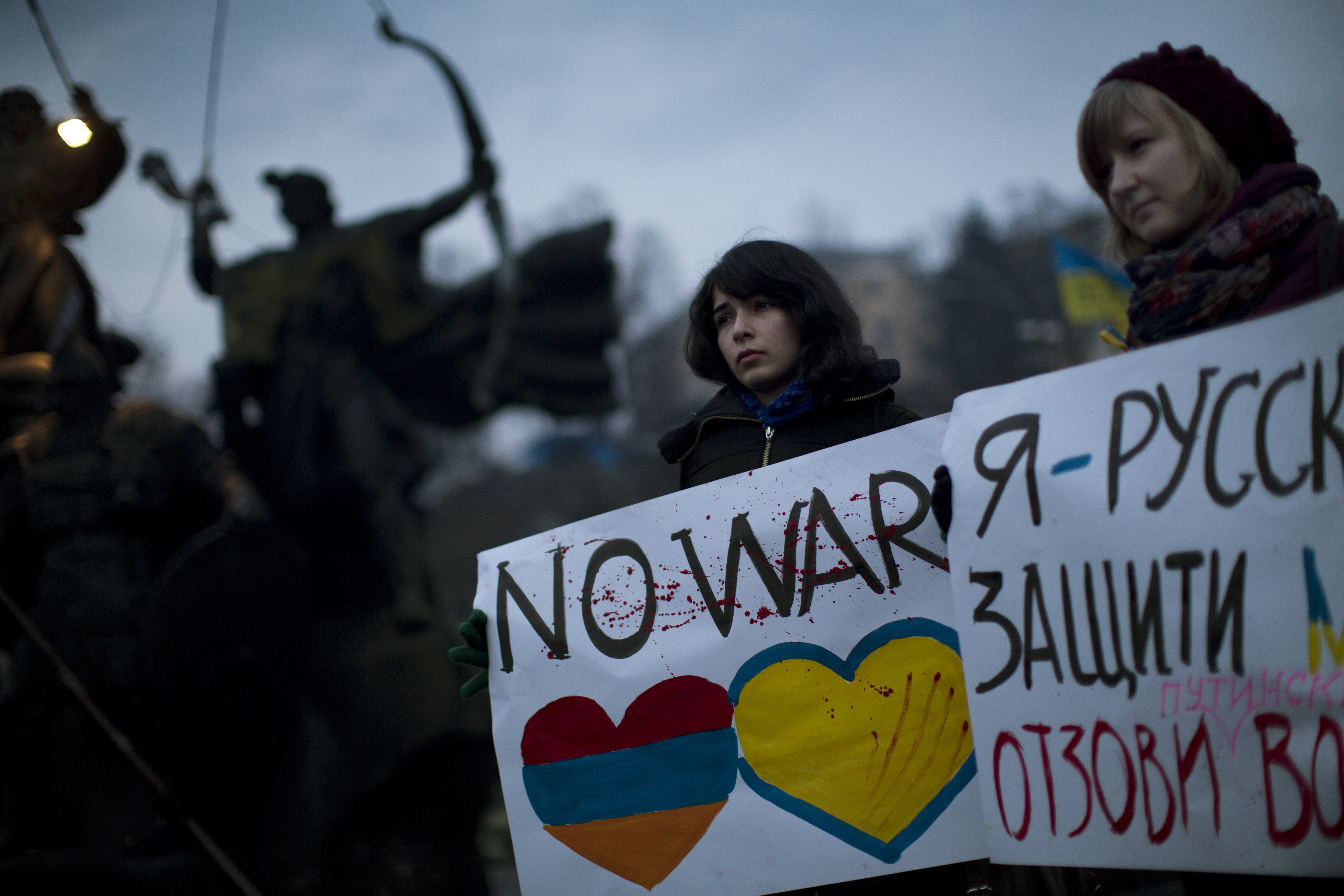 Ukrainian Maria, 23, right, and Vanui, 22, hold posters against Russia's military intervention in Crimea, in Kiev, Ukraine, Sunday, March 2, 2014. Russia's parliament approved a motion to use the country's military in Ukraine after a request from President Vladimir Putin as protests in Russian-speaking cities turned violent Saturday, sparking fears of a wide-scale invasion. The poster in the right side reads in Ukrainian: "I am from Russia, please protect me and remove the weapons and soldiers from Ukraine." (AP Photo/Emilio Morenatti) (AP)