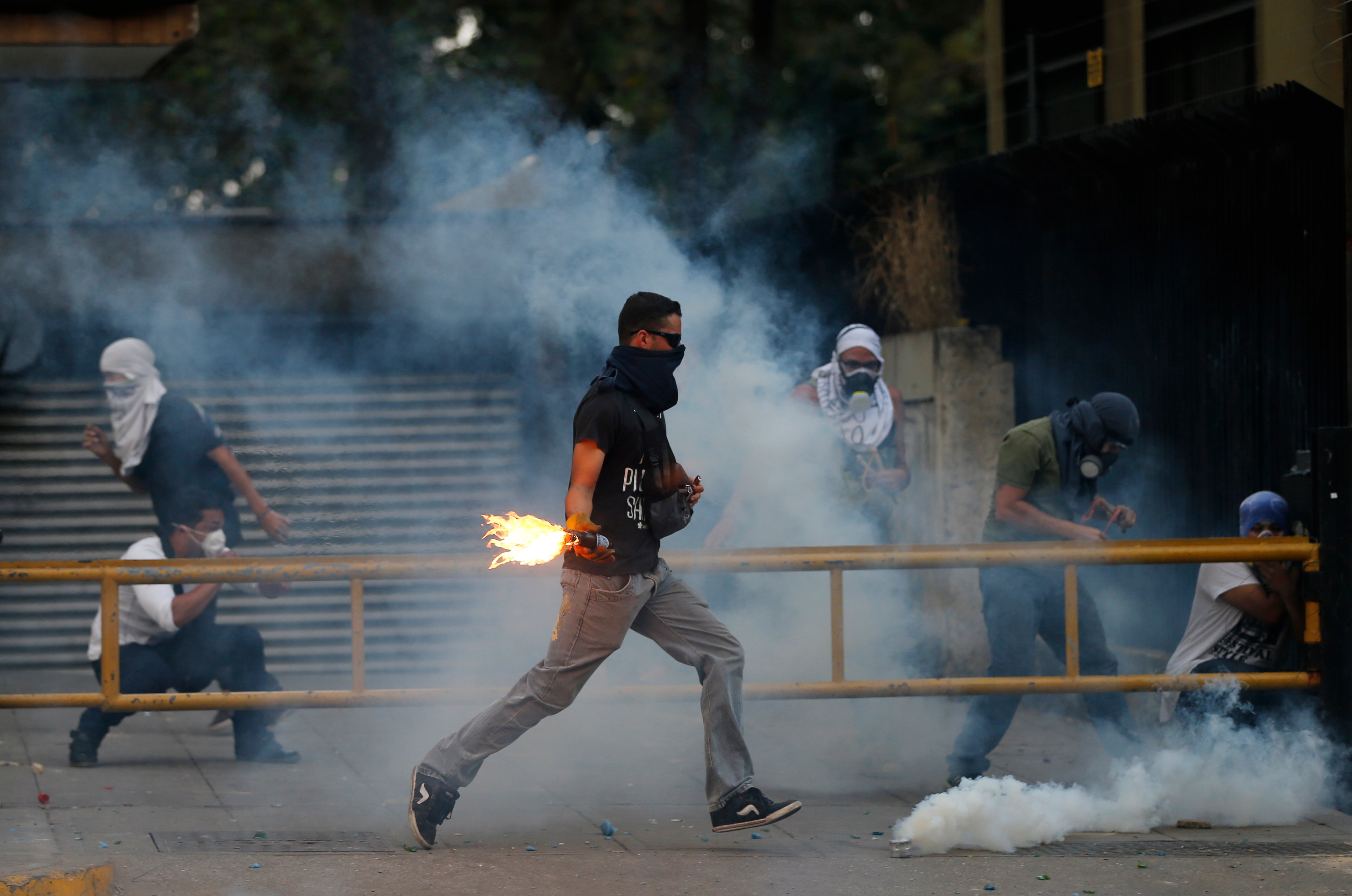 A demonstrator runs to throw a molotov bomb against Bolivarian National Police officers during clashes in Caracas, Venezuela, Thursday, March 6, 2014. (AP/Fernando Llano)