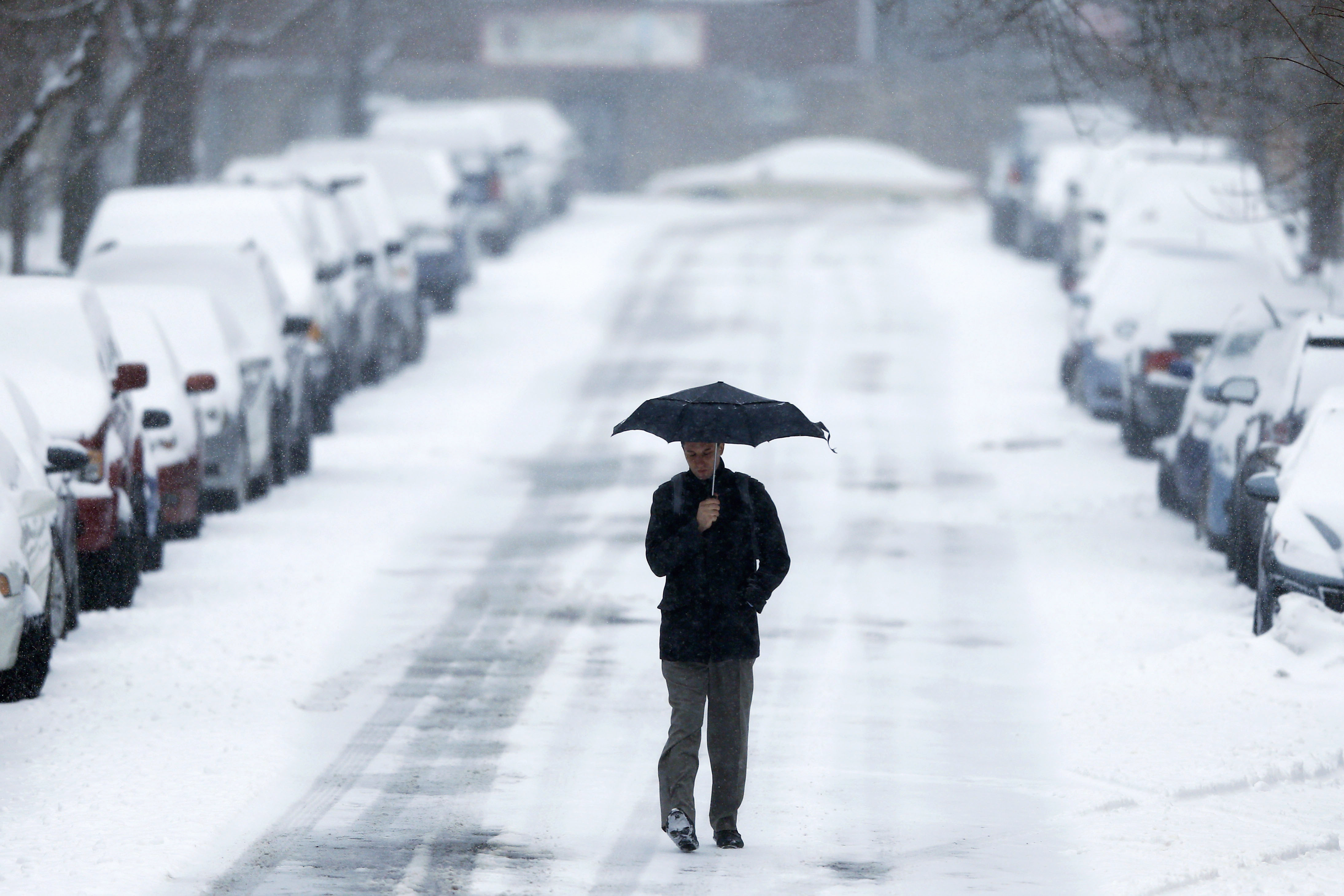 A morning commuter walks to a train station during a winter snowstorm Monday, March 3, 2014, in Philadelphia. Spring is in sight, but winter kept its icy hold on much of the country Monday, with up to a foot of snow and plummeting temperatures expected across the Mid-Atlantic states and up the East Coast. (AP Photo/Matt Rourke)
