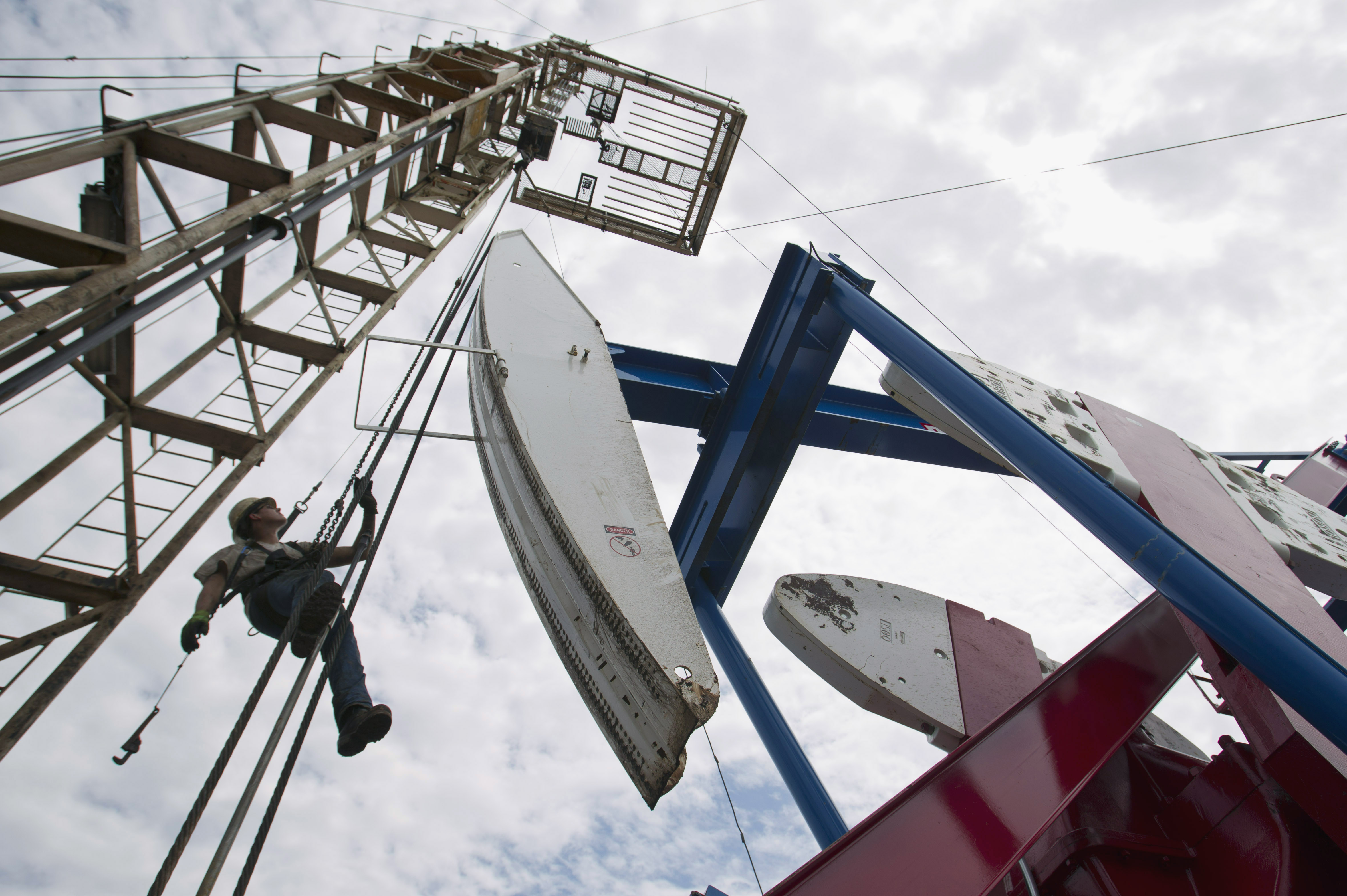 FILE - In this July 26, 2011, file photo, a worker hangs from an oil derrick outside of Williston, N.D. State data show that 1 billion barrels of oil have been produced from the rich Bakken shale formation in western North Dakota and eastern Montana. Data show that North Dakota has tallied 852 million barrels of Bakken crude, and Montana has produced about 151 million barrels. (AP Photo/Gregory Bull, File) (AP)
