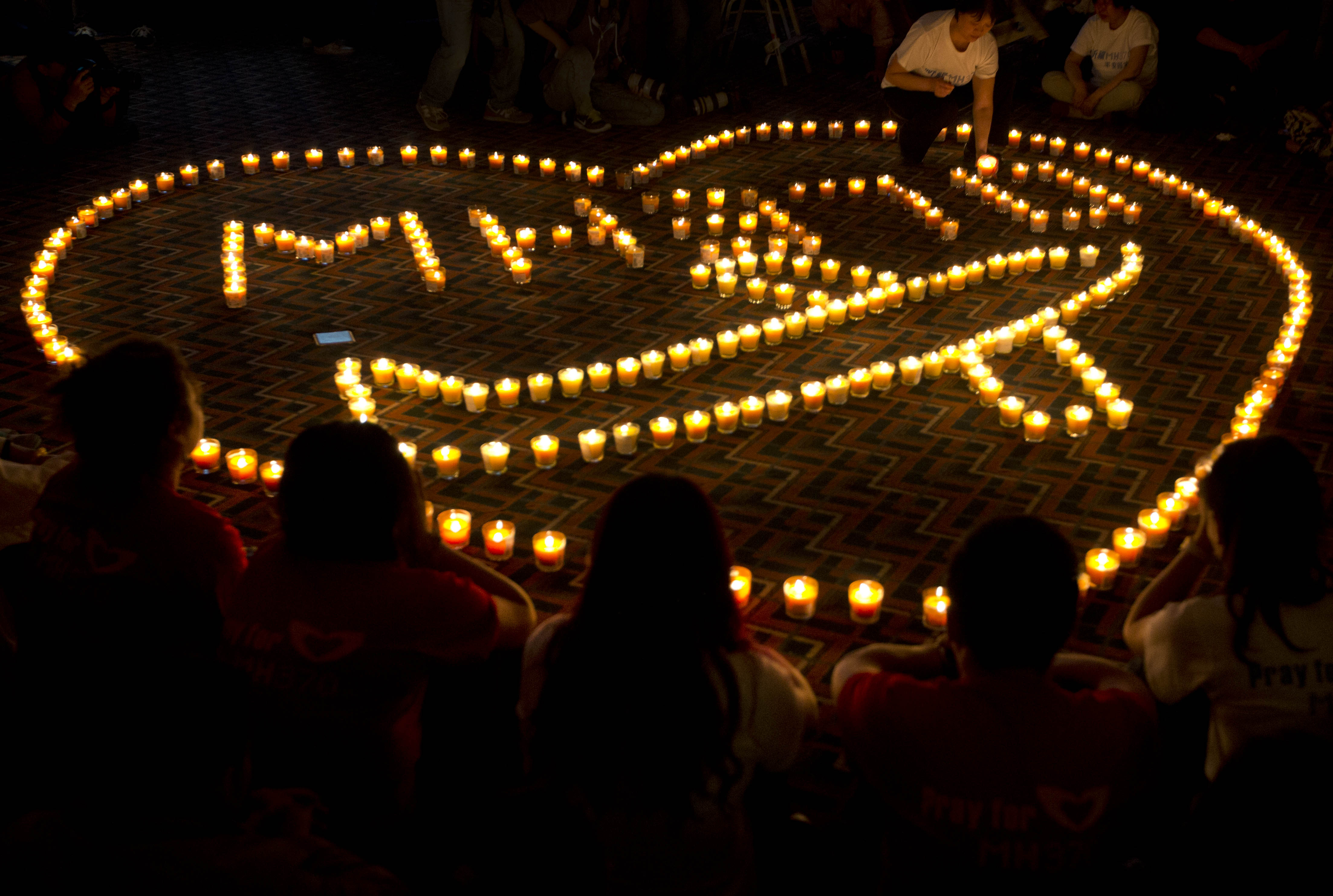 A woman arranges a candle as relatives of Chinese passengers onboard Malaysia Airlines Flight 370 offer prayer during a candlelight vigil for their loved ones at a hotel in Beijing, China, late Tuesday, April 8, 2014. An Australian ship is reported to have detected two distinct, long-lasting sounds underwater that are consistent with the 'pings' signal from aircraft black boxes, and is being seen as a possible advance in the month long hunt for the missing Malaysia Airlines jet, but the 'pings' still have to be verified.  (AP Photo/Andy Wong) (AP)