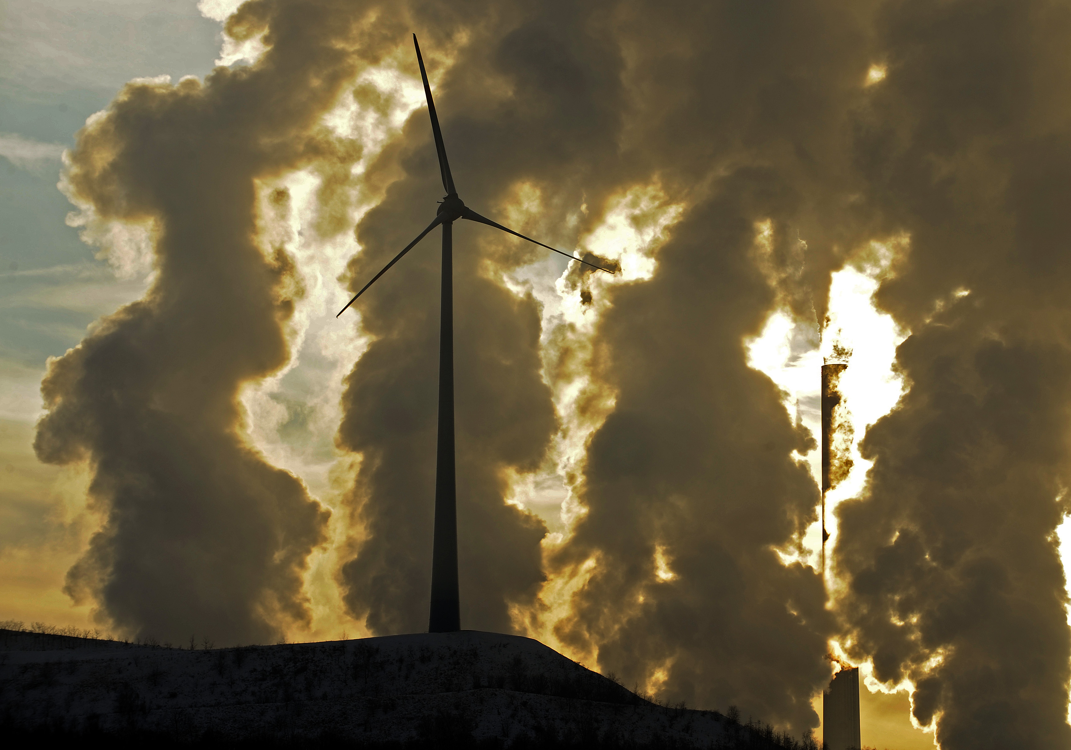FILE - In this Dec. 6, 2010 file photo a wind turbine is pictured in the in front of a steaming coal power plant in Gelsenkirchen, Germany. The U.N.s expert panel on climate change is preparing a new report this weekend outlining the cuts in greenhouse gases, mainly CO2 from the burning of fossil fuels, required in coming decades to keep global warming in check.() (AP Photo/Martin Meissner, File)