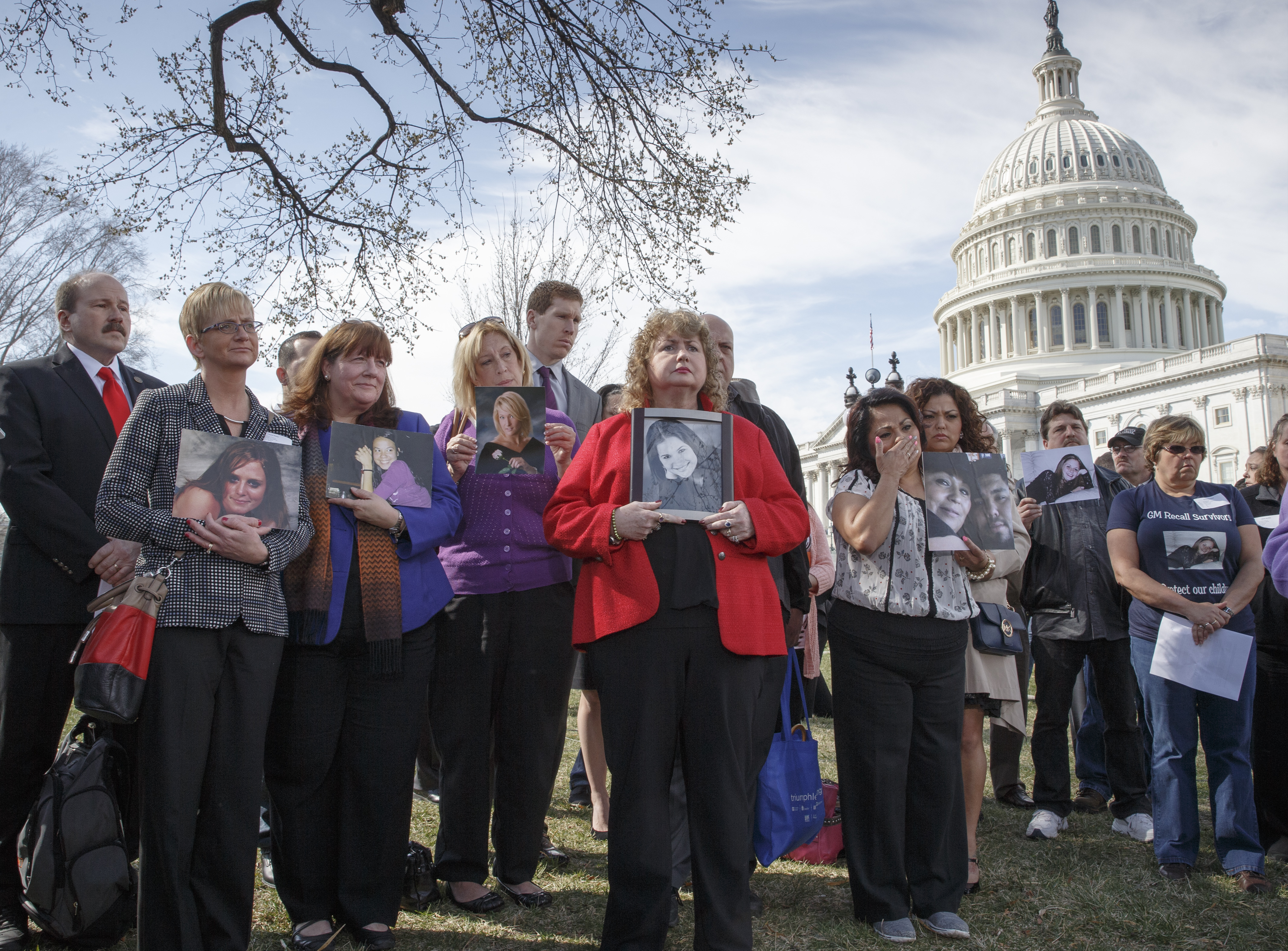 Calling themselves GM Recall Survivors, families of victims of a General Motors safety defect in small cars hold photos of their loved ones (AP)