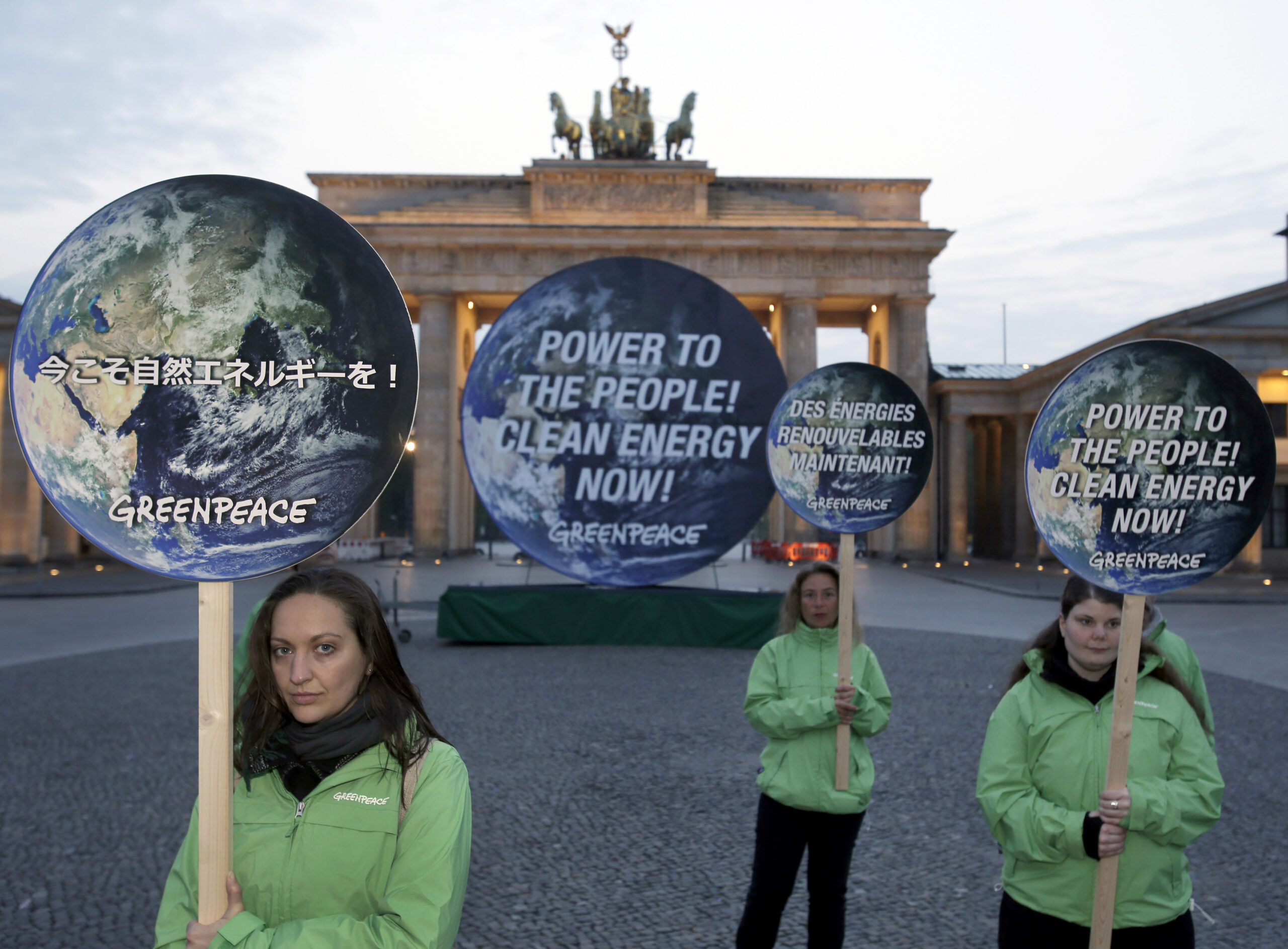 Activists of the international environmentalist organization Greenpeace pose with posters in front of the Brandenburg Gate in Berlin, Germany, Sunday, April 13, 2014  to support clean energy. After a one week meeting of the Intergovernmental Panel on Climate Change in Berlin the final document which is released on Sunday is expected to say that a global shift to renewable energy from fossil fuels like oil and coal are required to avoid potentially devastating sea level rise, flooding, droughts and other impacts of warming. (AP Photo/Michael Sohn) (Michael Sohn)