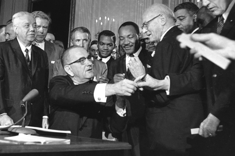 U.S. President Lyndon Johnson passes out some of the 72 pens he used to sign the civil rights bill in Washington D.C. on July 2, 1964. (AP)