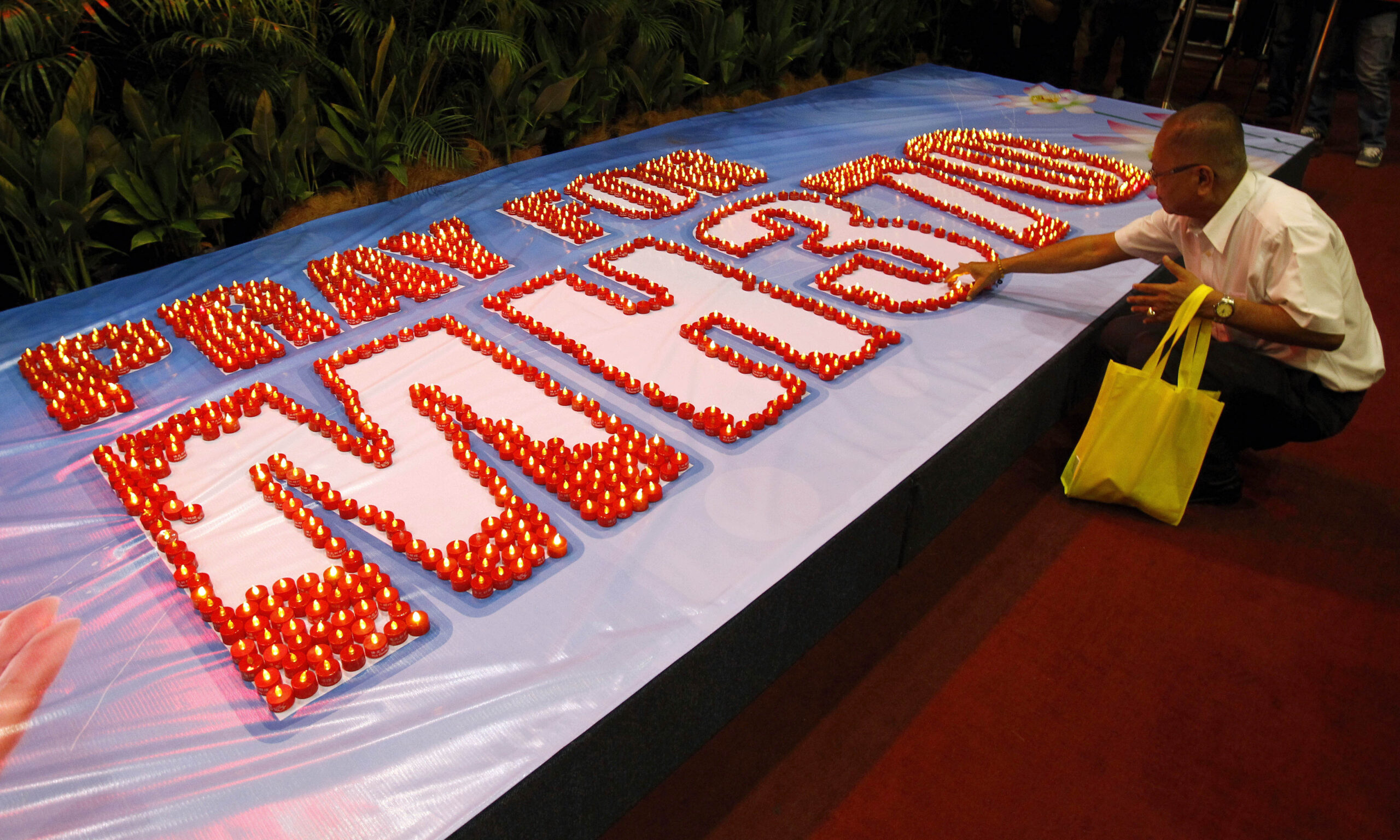A man places a LED candle after a mass prayer for the missing Malaysia Airlines Flight MH370, in Kuala Lumpur, Malaysia, Sunday, April 6, 2014. The head of the multinational search for the missing Malaysia airlines jet says that electronic pulses reportedly picked up by a Chinese ship are an encouraging sign but stresses they are not yet verified. (AP Photo/Lai Seng Sin) (Lai Seng Sin)