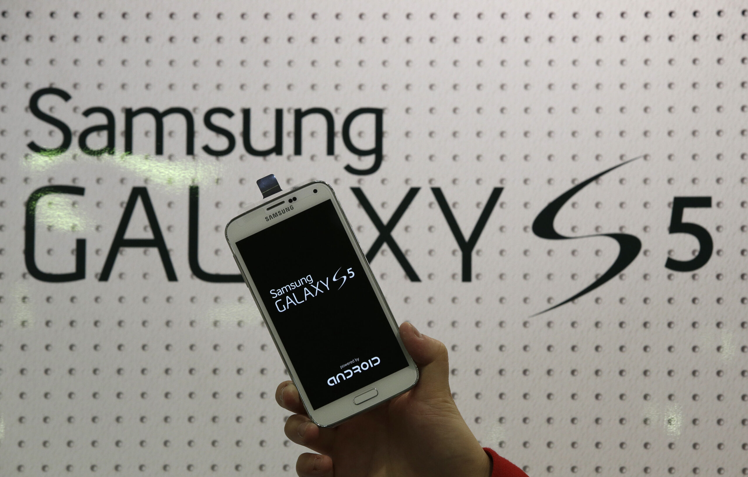 An employee shows Samsung's Galaxy S5 smartphone at a mobile phone shop in Seoul, South Korea, Thursday, March 27, 2014. The global launch of Samsung's latest smartphone is being upstaged by South Korean mobile network companies. SK Telecom, South Korea's largest mobile carrier, said it will start selling the Galaxy S5 on Thursday, two weeks before the scheduled sales launch on April 11. (AP Photo/Lee Jin-man) (Lee Jin-man)