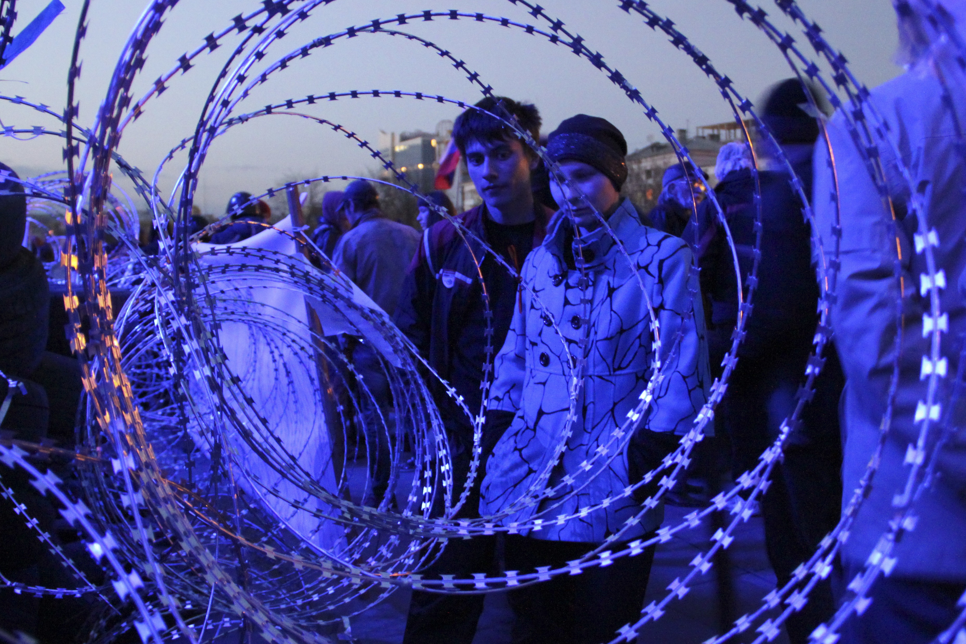 People gather near a barricade with razor wires at the regional administration building in Donetsk, Ukraine, late Monday, April 7, 2014. Outside the Donetsk building, a barricade of car tires and razor wire was built up to thwart police from retaking it. Interfax cited police in Donetsk as saying one armed group fired into the air and attempted to seize the regional state television broadcaster Monday but retreated after police and guards in the building also fired warning shots into the air. (AP Photo/Alexander Ermochenko) (AP)