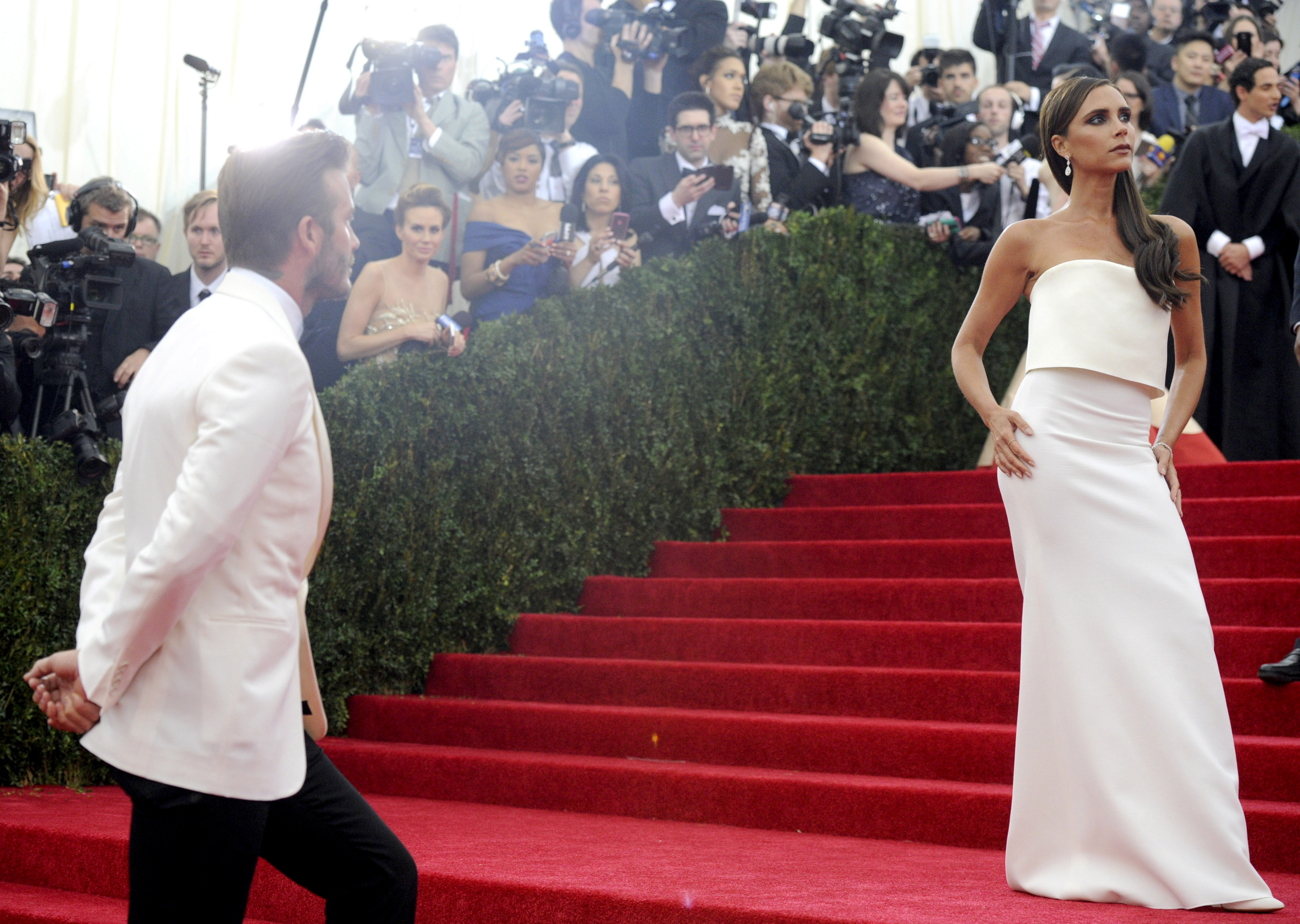 David Beckham, left, looks on as his wife Victoria Beckham poses at the Metropolitan Museum of Art's Costume Institute benefit gala celebrating "Charles James: Beyond Fashion" on Monday, May 5, 2014, in New York. (Photo by Charles Sykes/Invision/AP) (Charles Sykes/invision/ap)