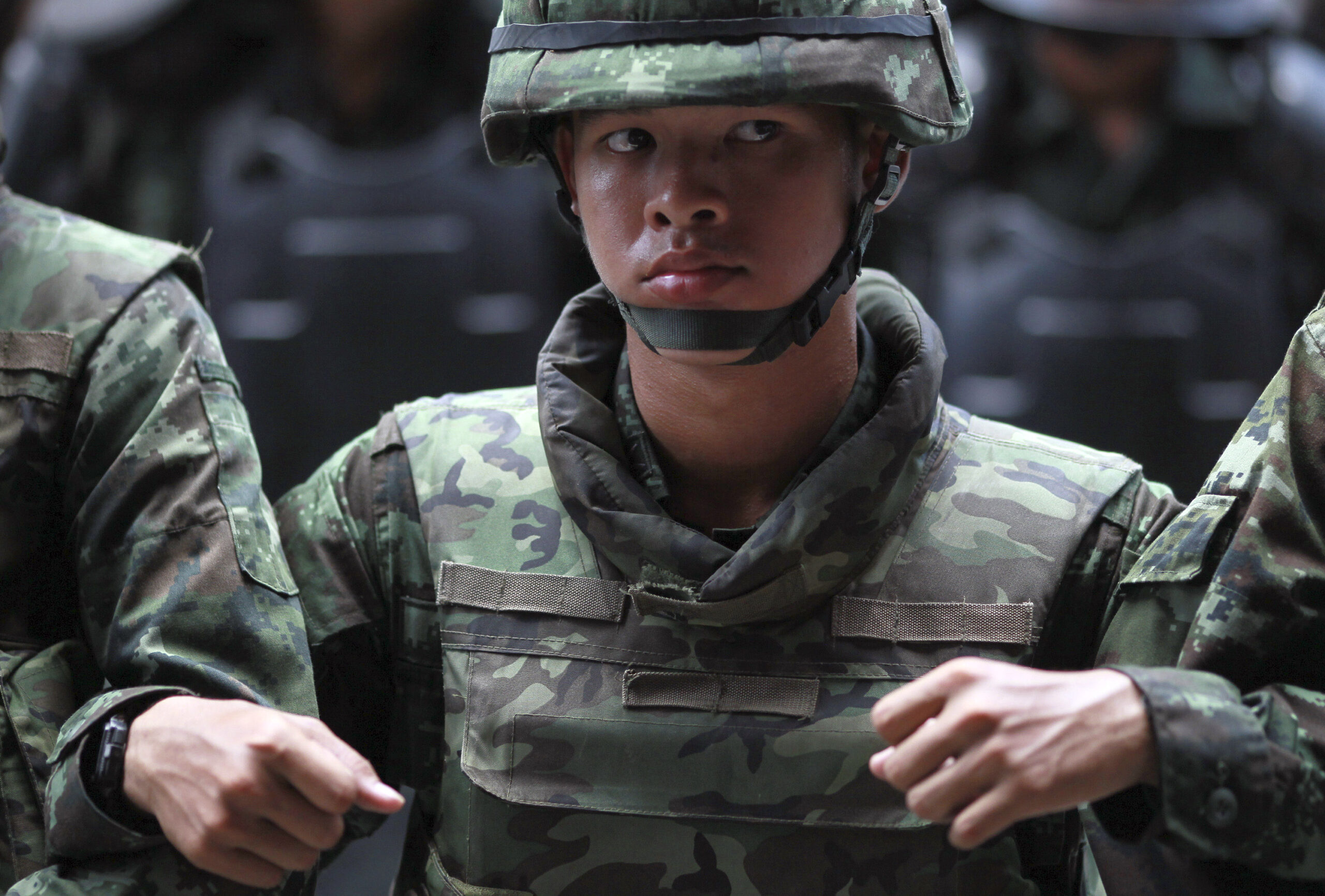 Thai soldiers link arms as they monitor the protest against the coup outside a shopping in Bangkok, Thailand Saturday, May 24, 2014. Thailand's coup leaders said Saturday they will keep former Prime Minister Yingluck Shinawatra, Cabinet members and anti-government protest leaders detained for up to a week to give them "time to think" and to keep the country calm. They also summoned outspoken academics to report to the junta. (AP Photo/Wason Wanichakorn) (Wason Wanichakorn)