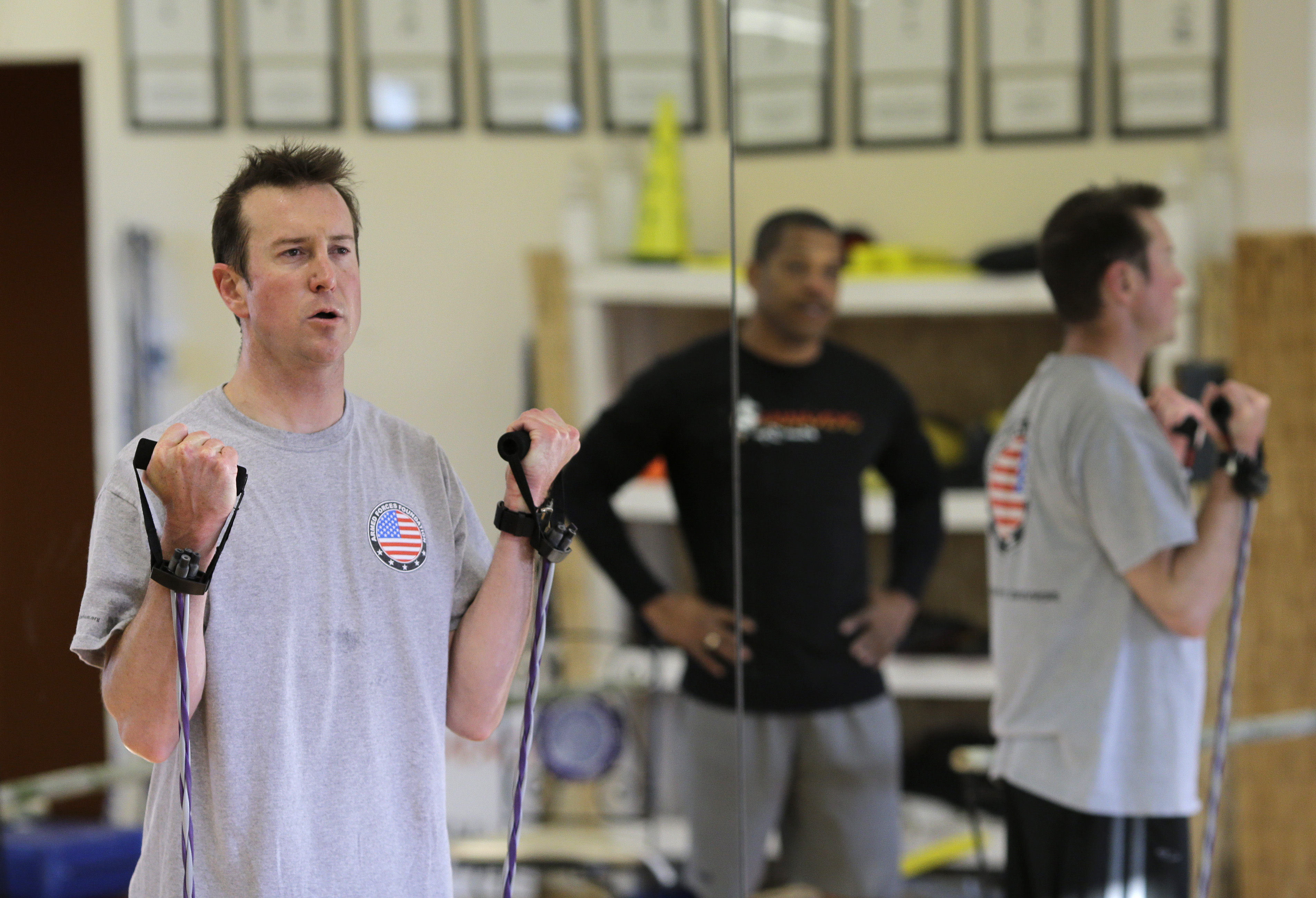 In this photo taken on April 24, 2014, race car driver Kurt Busch works out at a gym in Ellicott City, Md., as trainer Stanley Crump, back right, watches. On Memorial Day weekend, NASCAR's bad boy is trying to own the title of baddest man on the track by pulling off racing's version of an IronMan triathlon. In a single day, he'll try and race in the Indianapolis 500 and the Coca-Cola 600, with a race or two against the clock thrown in. (AP Photo/Patrick Semansky) (AP)