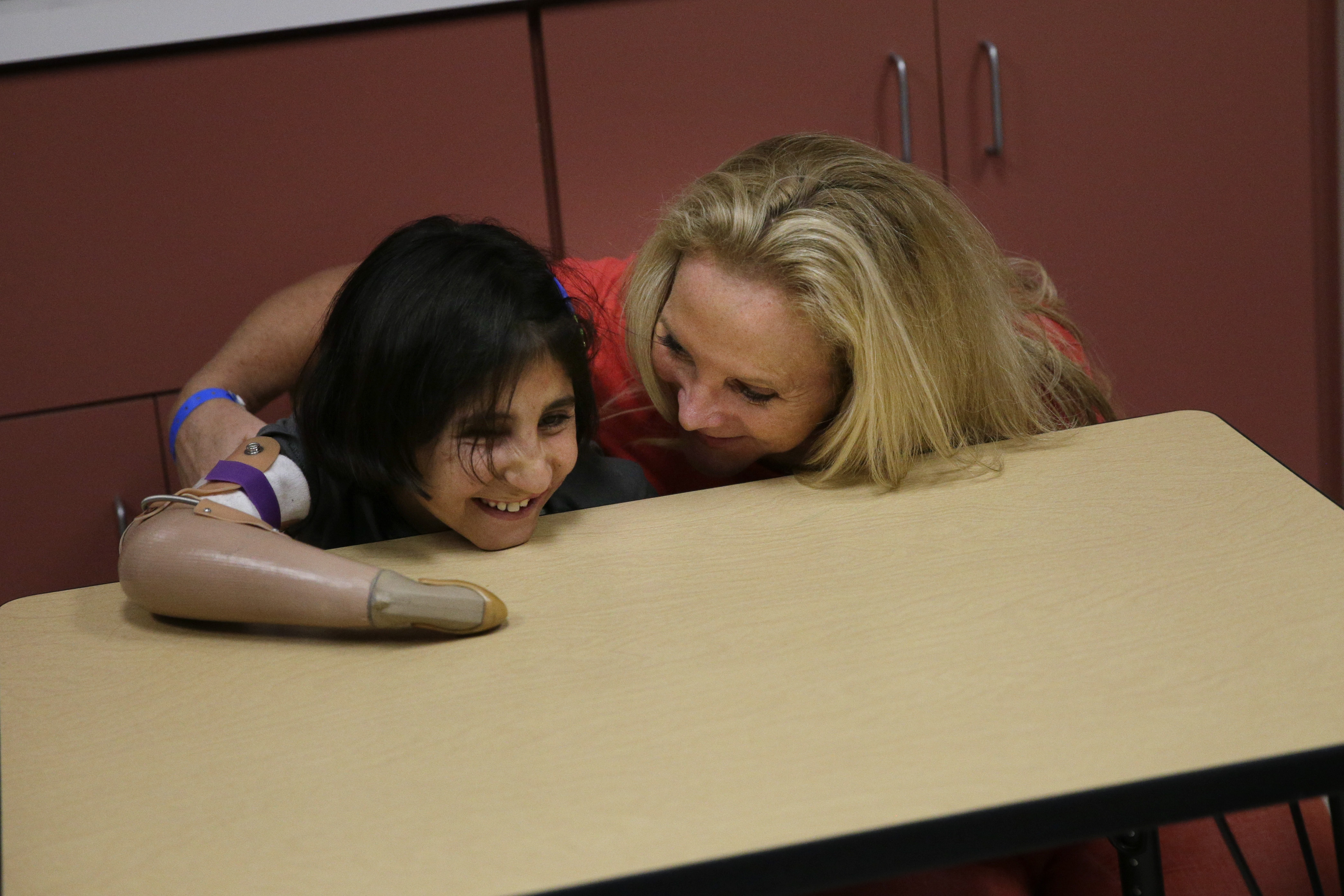 Shah Bibi Tarakhail, a six-year-old Afghan girl whose love of painting won the hearts of U.S. doctors who fitted her with a prosthetic, is tickled by her host mother, Ann Drummond, at Shriners Hospital for Children on Thursday, June 19, 2014, in Los Angeles. Shah Bibi Tarakhail, who lost her right arm and right eye when she picked up a grenade following a firefight between U.S. and Taliban forces in her village near the Pakistan border, returned to the United States on Thursday, after the group that sponsored her first visit said it learned her newfound celebrity made her a subject of death threats at home. (AP Photo/Jae C. Hong) (AP)