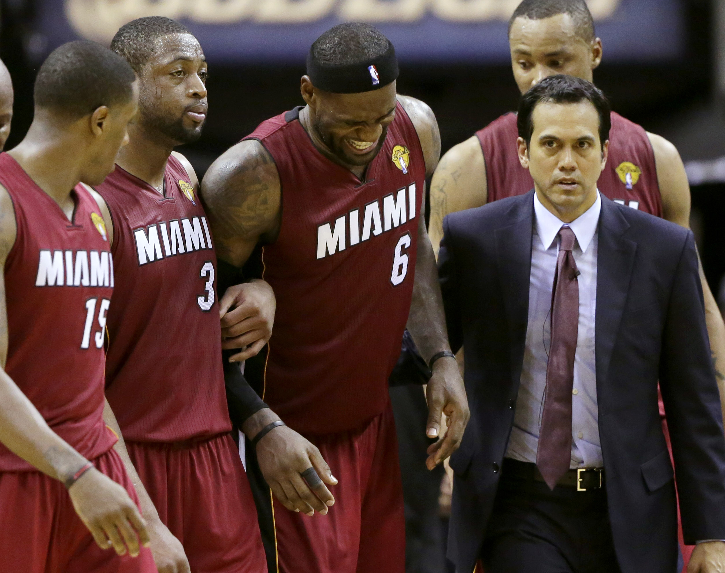 Miami Heat forward LeBron James (6) is helped from the court by guard Mario Chalmers (15), guard Dwyane Wade (3), Erik Spoelstra, front, right, and Rashard Lewis, right rear, during the second half in Game 1 of the NBA basketball finals on Thursday, June 5, 2014 in San Antonio. (AP Photo/Eric Gay) (Eric Gay)
