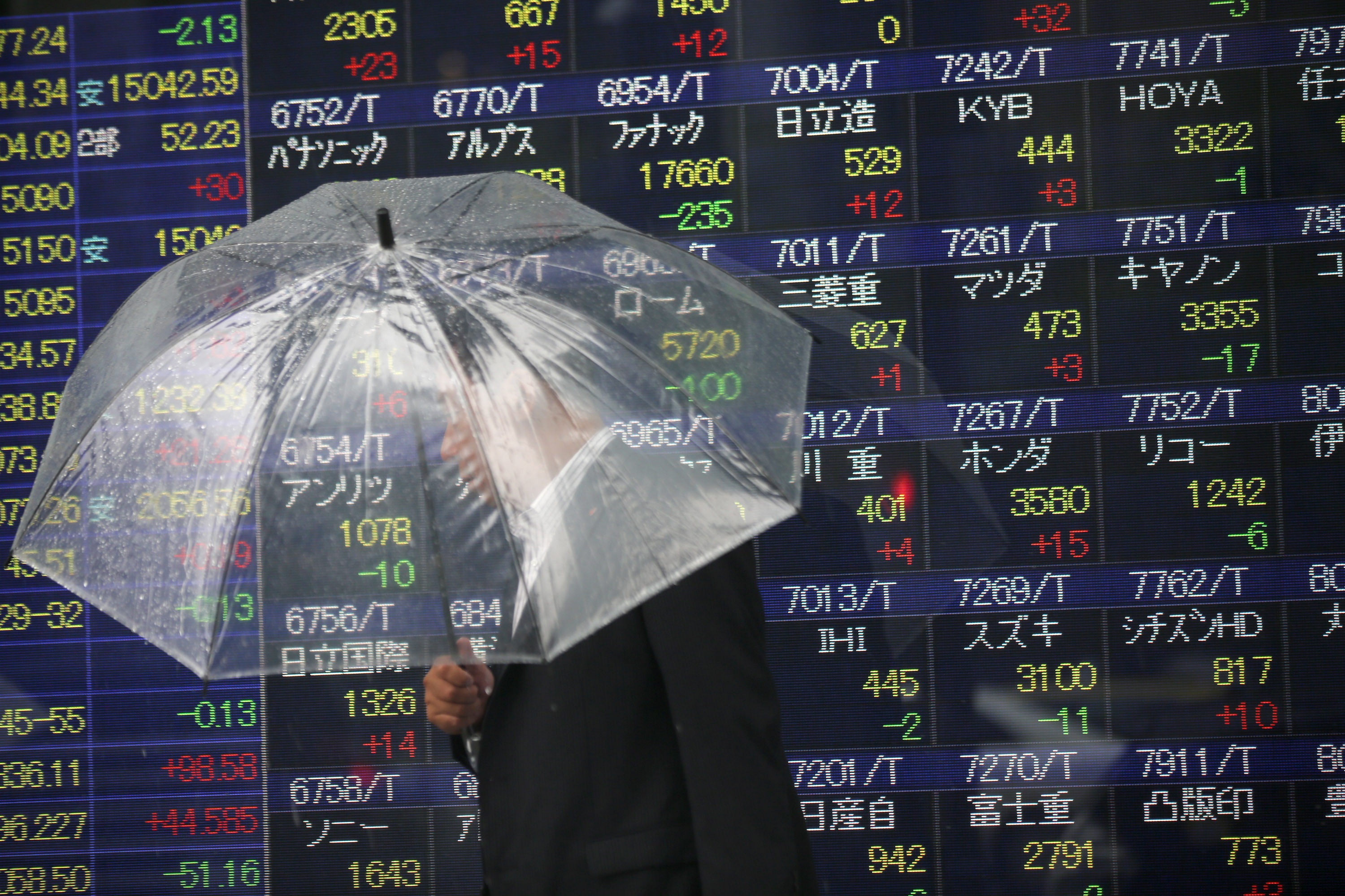 FILE - In this June 6, 2014 file photo, a man holding an umbrella walks past an electronic stock indicator of a securities firm, in Tokyo. The Treasury Department releases foreign holdings data for April on Monday, June 16, 2014. (AP Photo/Eugene Hoshiko, File) (AP)