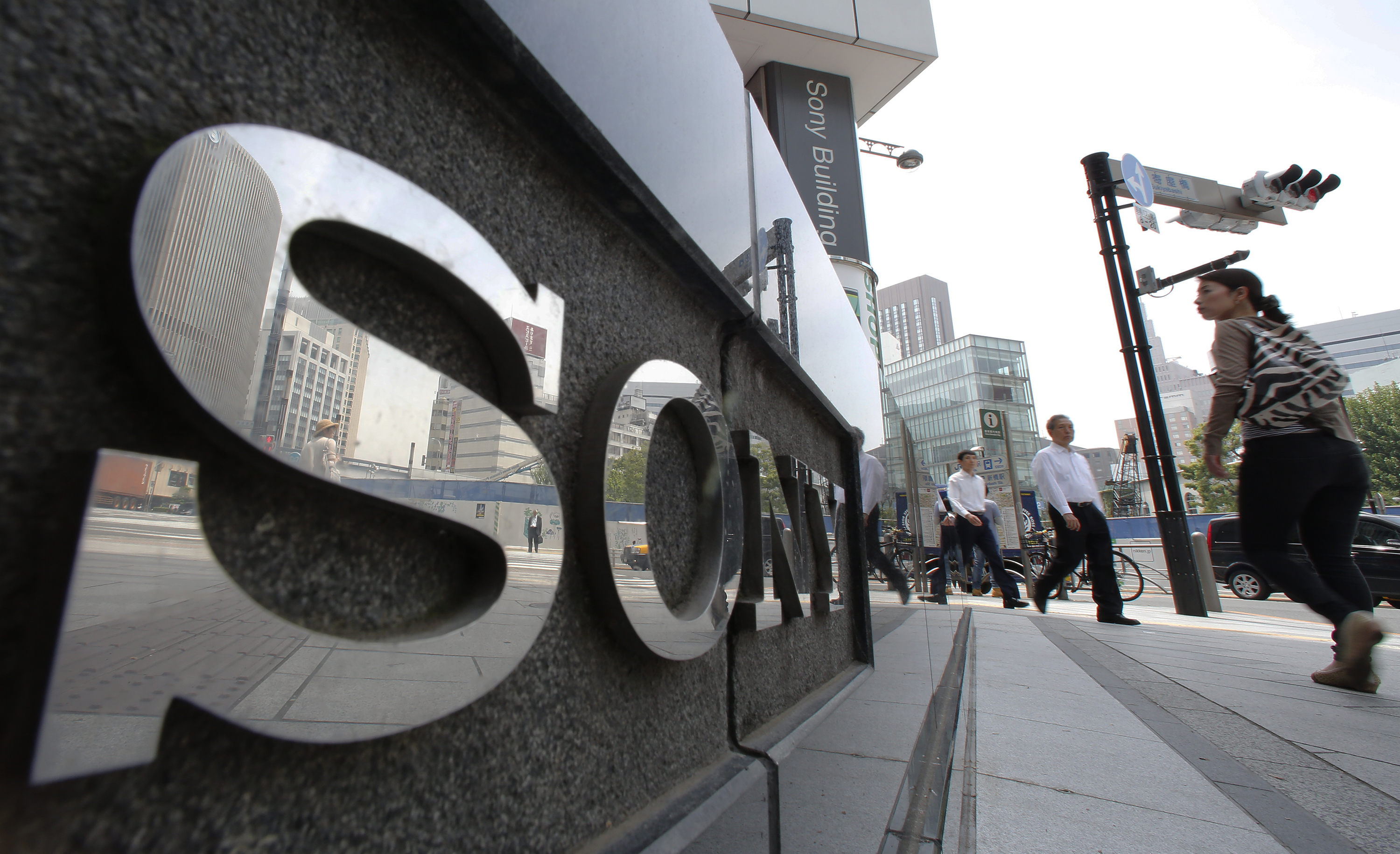 FILE - In this May 14, 2014 file photo, people walk by the Sony Building at Ginza shopping district in Tokyo. Sony shareholders voted Thursday, June 19 to keep Chief Executive Kazuo Hirai and other top executives after heckling them about the Japanese electronics and entertainment company's continuing losses. (AP Photo/Shizuo Kambayashi, File) (AP)