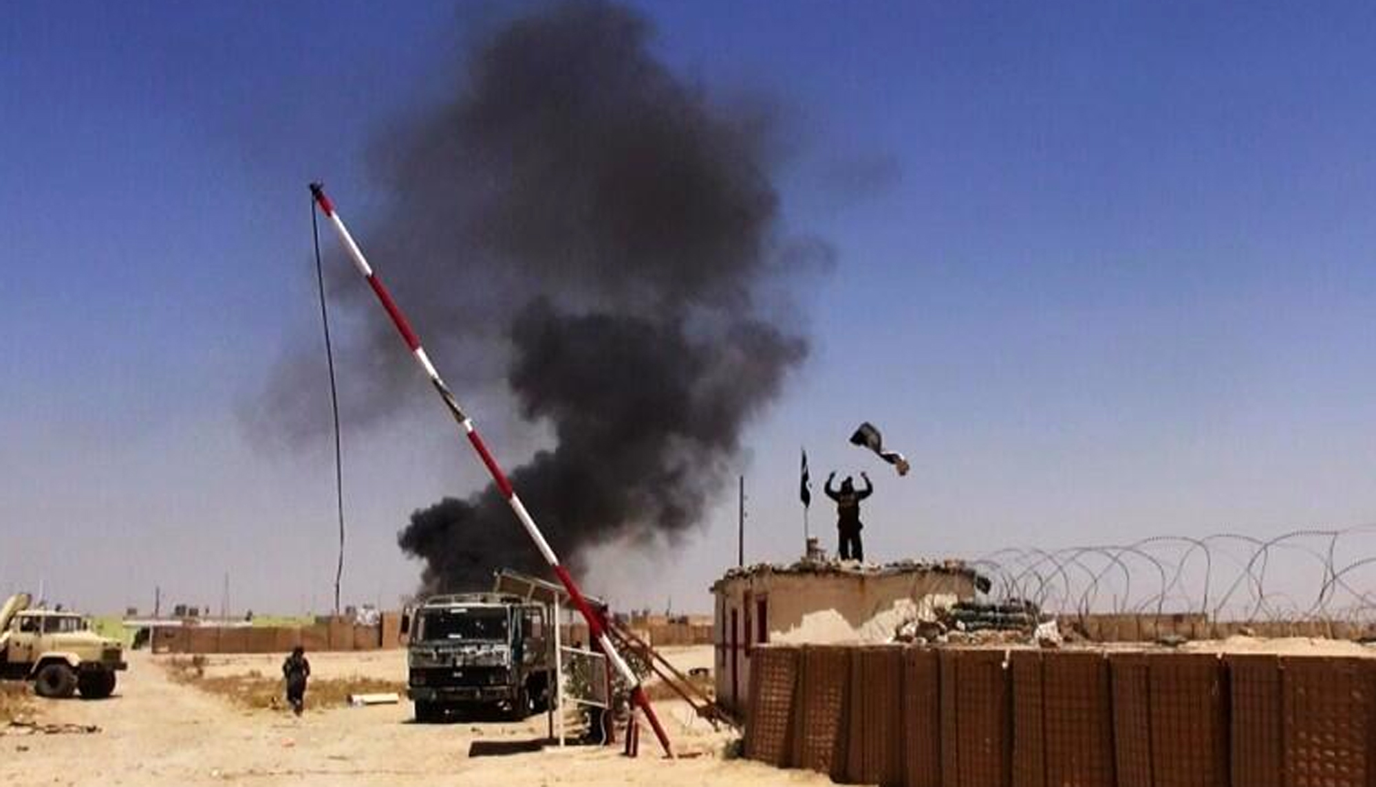 Militants from the al-Qaida-inspired Islamic State of Iraq and the Levant (ISIL) people raising their flag at the entrance of an army base in Ninevah Province. Iraq. (AP)