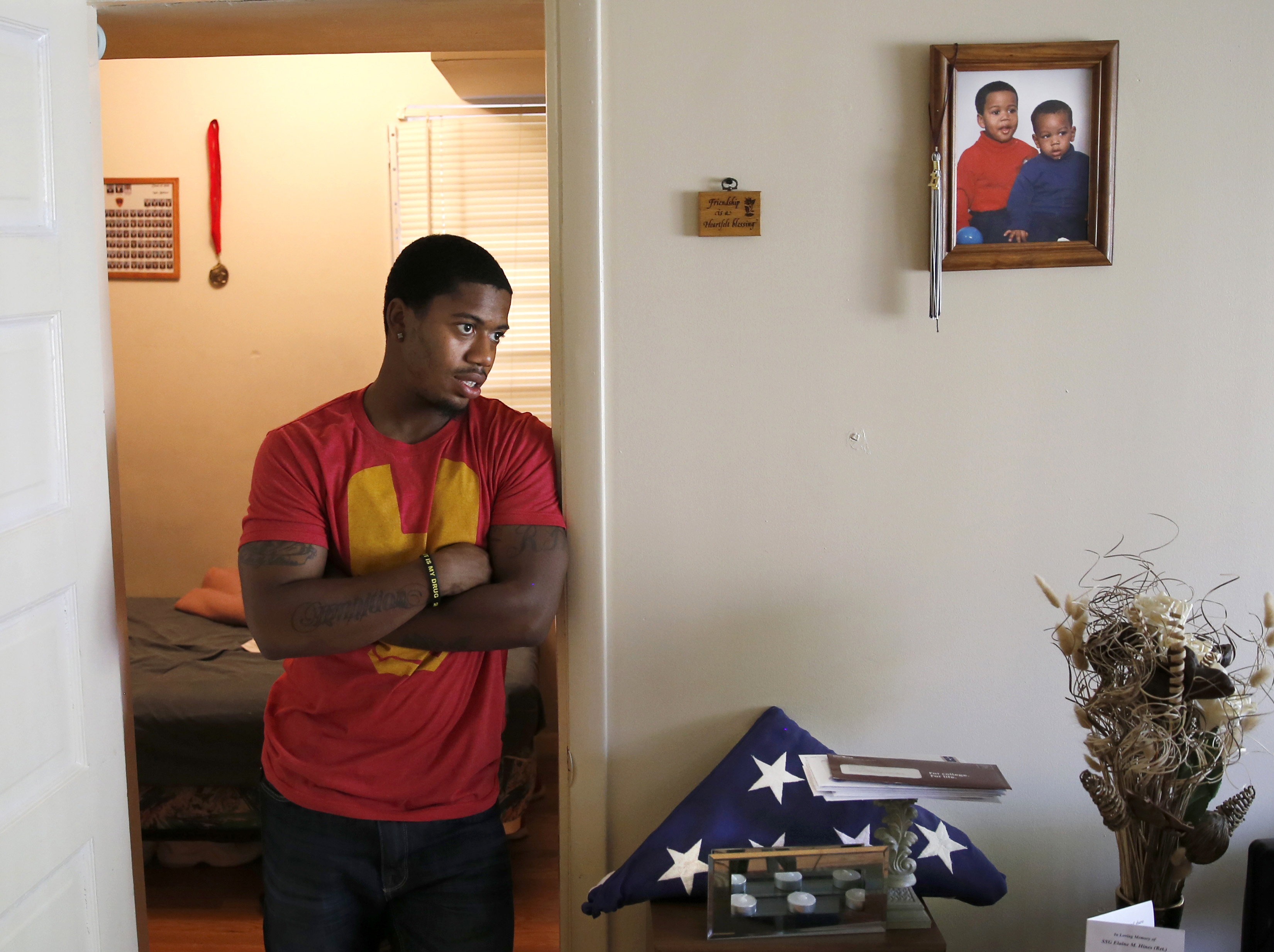 In this May 10, 2014, photo, Rayvaughn Hines stands in the doorway of his bedroom where a photograph of him and his little brother Willie Brown Jr., hangs on the wall and a military funeral flag for his grandmother, Elaine Hines, sits in his mother Shireille's home in Chicago. At 22, Hines, a Gates Millennium scholar and Urban Prep class of 2010 graduate, recently earned his psychology degree from the University of Virginia. (AP Photo/Charles Rex Arbogast) (AP)