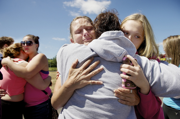 Brandi Wilson, left, and her daughter Trisha, right, embrace Trish Hall, a mother waiting for her student in Wood Village, Ore., after a shooting at Reynolds High School, June 10, 2014, in nearby Troutdale. (AP/Troy Wayrynen)