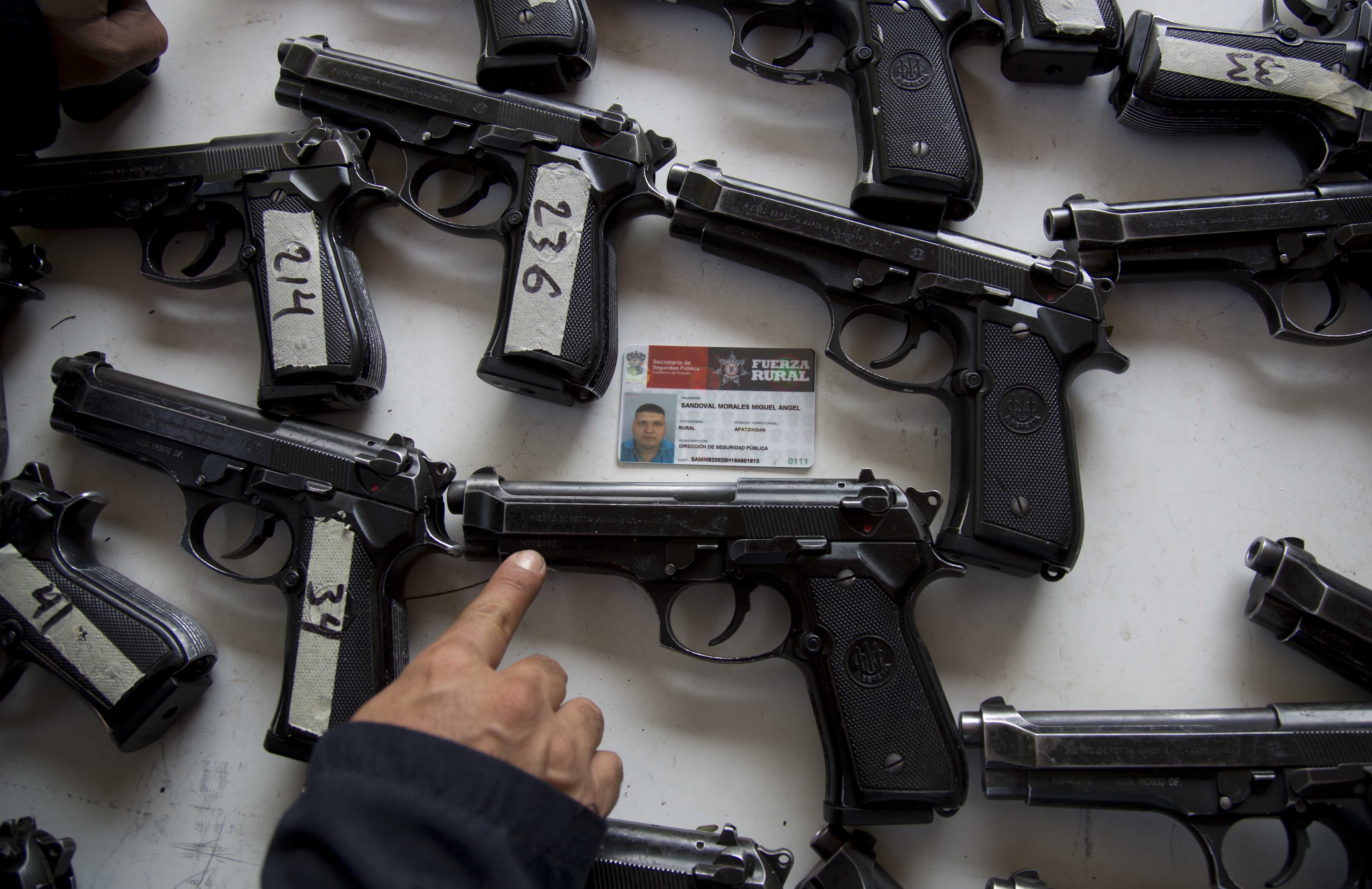 A federal police looks for the assigned weapon that corresponds to the rural police's identification card before the start of a ceremony in Tepalcatepec, Mexico, Saturday, May 10, 2014. (Associated Press)
