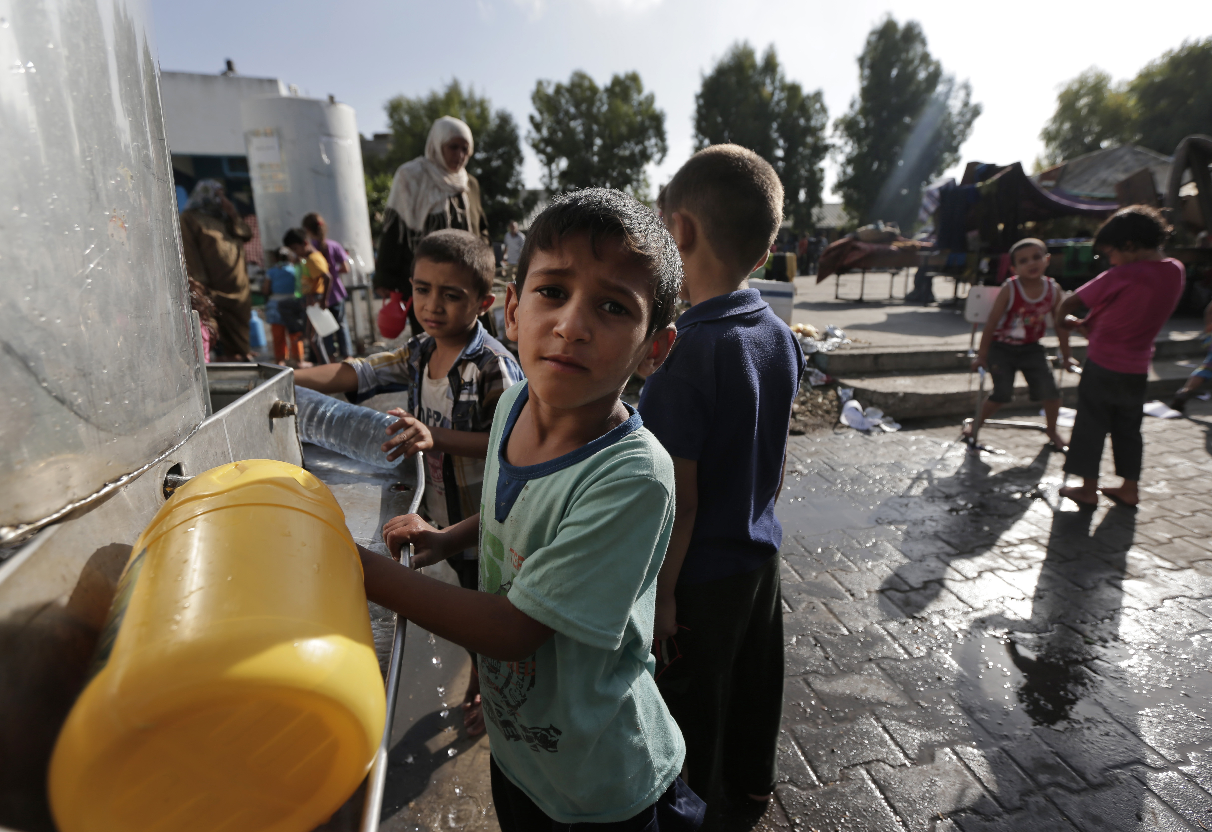 Displaced Palestinian children collect water, at a different U.N. school in Jebaliya refugee camp, northern Gaza Strip, Wednesday, July 30, 2014.  Some 3,300 Gazans seeking shelter from the fighting had been crowded into the U.N. school in Jebaliya refugee camp when it was hit by a series of Israeli artillery shells on Wednesday. (AP Photo/Lefteris Pitarakis)
