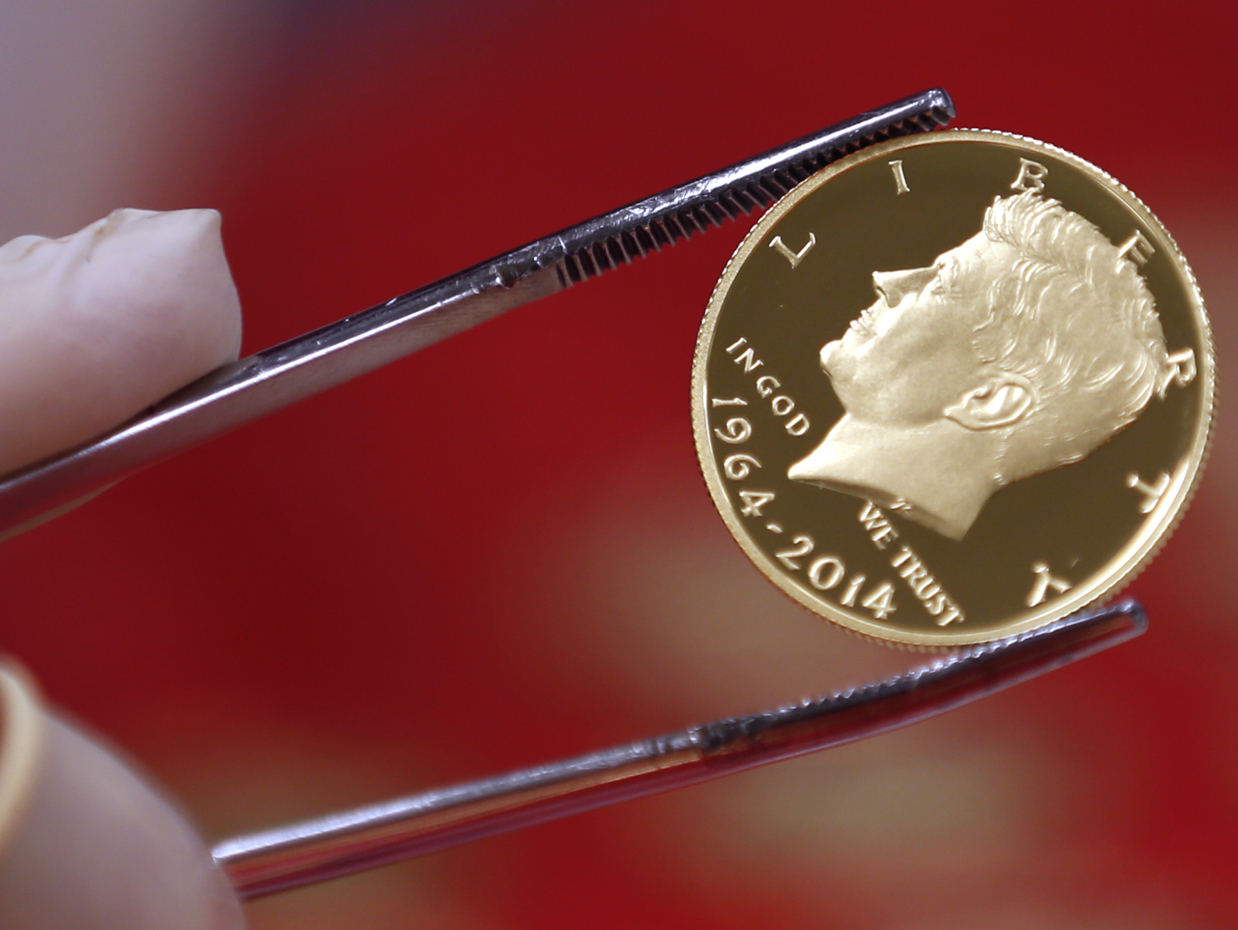 A newly-stamped gold coin of President John F. Kennedy is examined at the U.S. Mint at West Point on Tuesday, July 22, 2014, in West Point, N.Y. Kennedy is getting a new look on the new coin that is being made by the mint to mark the 50 years since the slain president debuted on a half-dollar. (AP Photo) (AP)