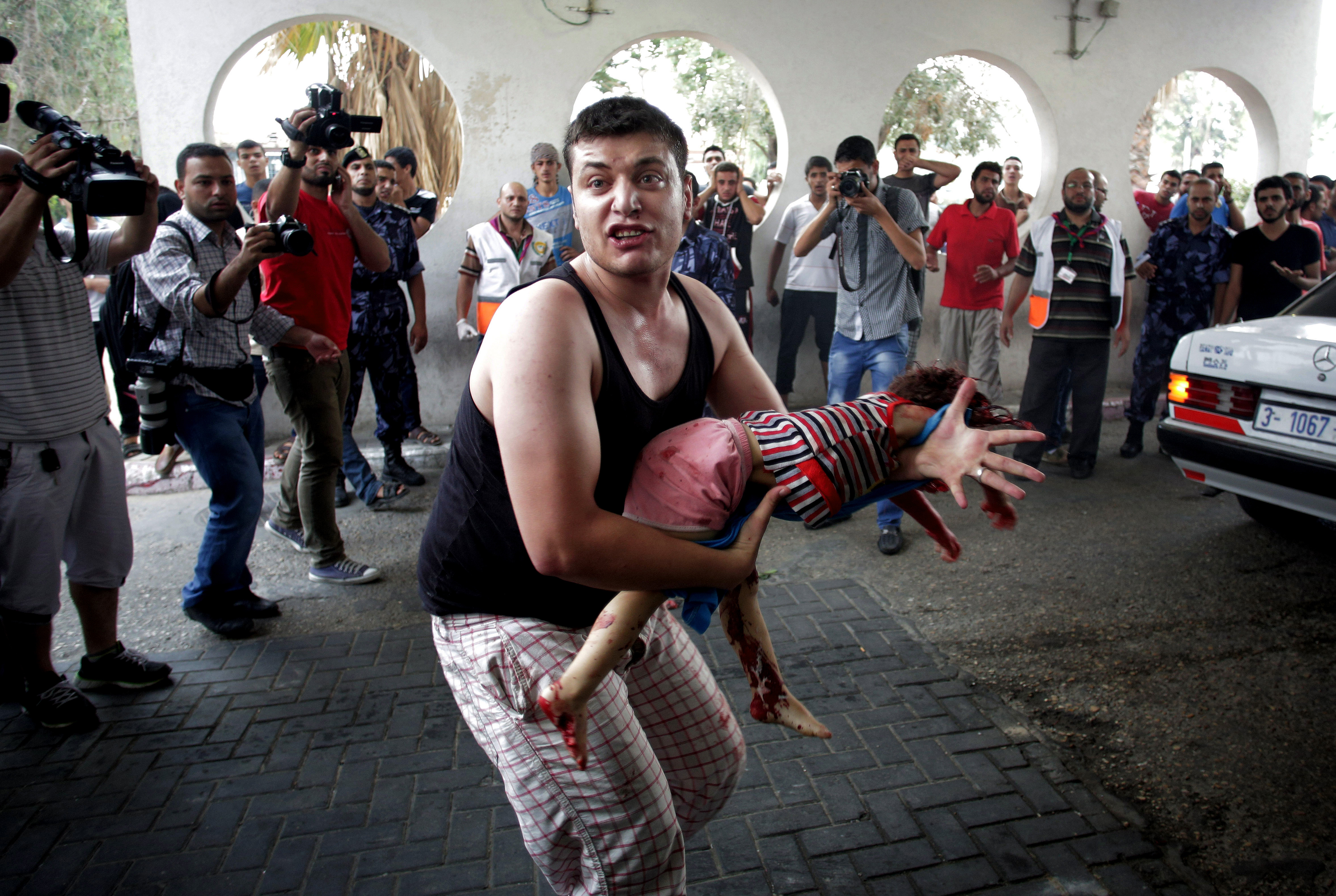 A Palestinian man carries the lifeless body of a child to an emergency room at Shifa hospital in Gaza City last week. (AP/Khalil Hamra)