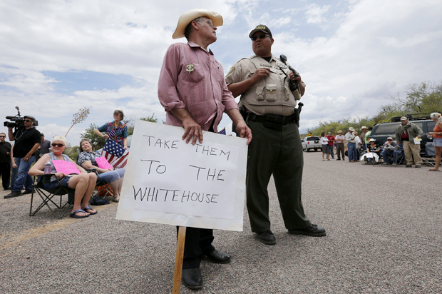 Eldon Rhodes talks with a Pinal County Sheriff officer as people demonstrate against the arrival of undocumented immigrants in Oracle, Arizona July 15, 2014. (Reuters/Nancy Wiechec)