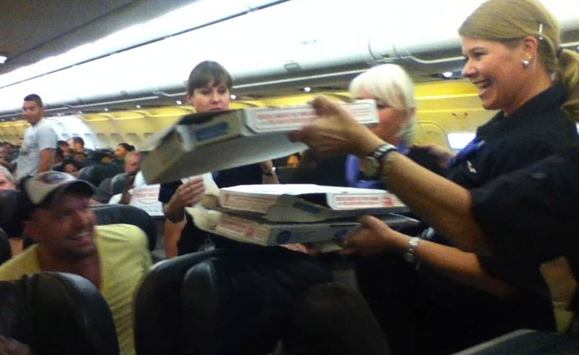 In this photo taken Monday, July 7, 2014, a Frontier Airlines flight attendant passes out pizza to passengers aboard a Denver-bound flight diverted to Cheyenne, Wyo. The airplane pilot treated his passengers to the pizza after they were diverted. (AP Photo/Logan Marie Torres) (AP)