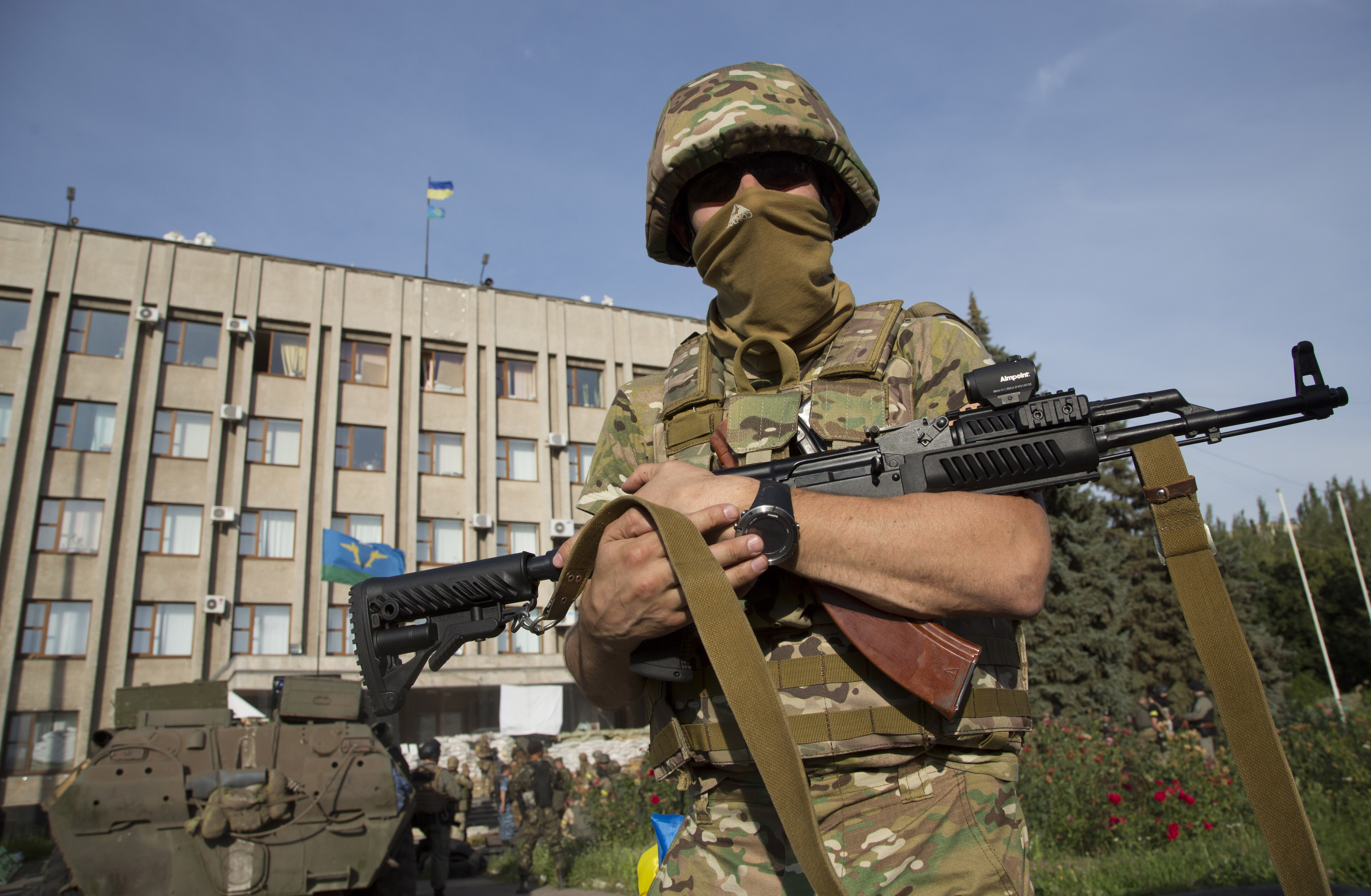 An Ukrainian government army soldier stands in front of the government building with a Ukrainian flag on the roof in the city of Slovyansk. (AP/Dmitry Lovetsky)