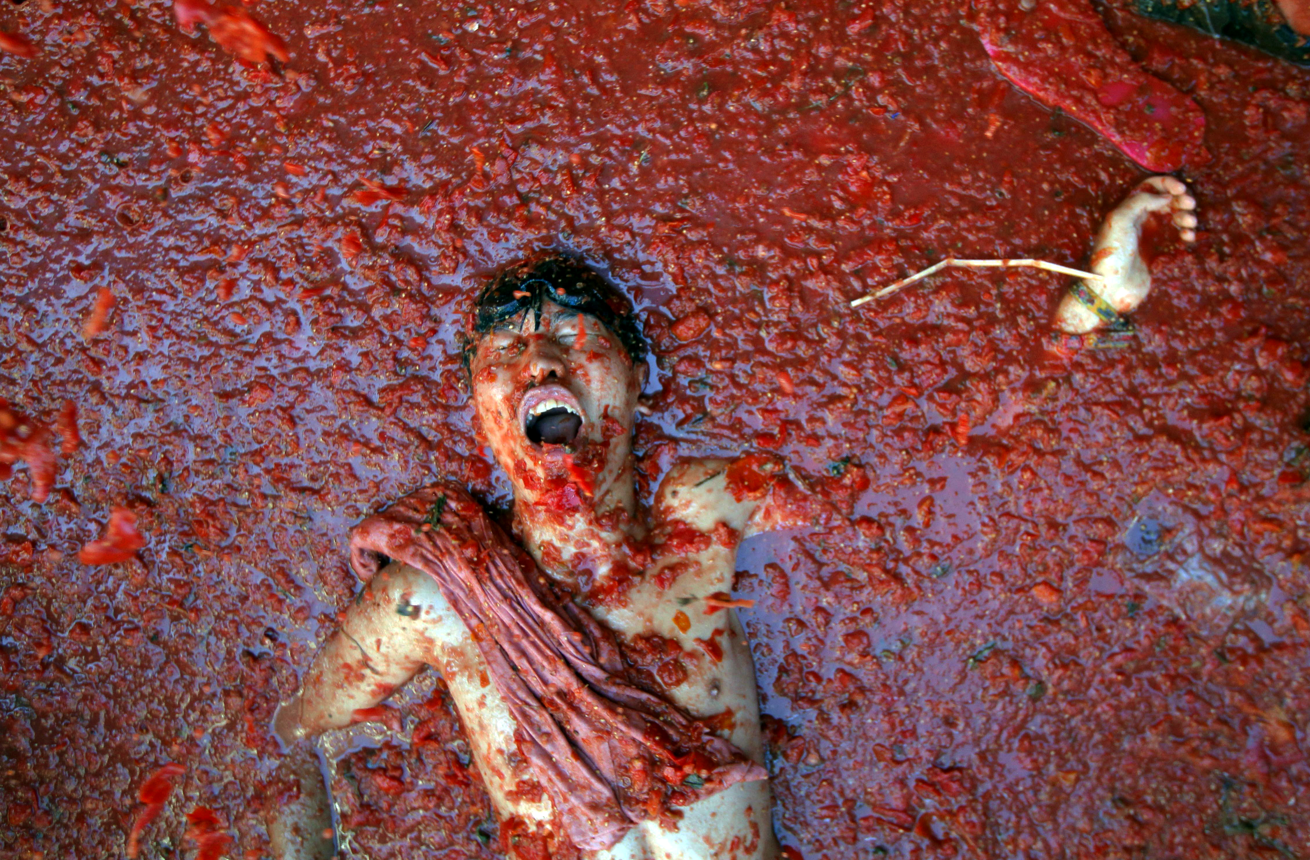 AP10ThingsToSee- A man lies in a puddle of squashed tomatoes, during the annual "tomatina" tomato fight fiesta in the village of Bunol, 50 kilometers outside Valencia, Spain, Wednesday, Aug. 27, 2014. (AP Photo/Alberto Saiz) (AP)