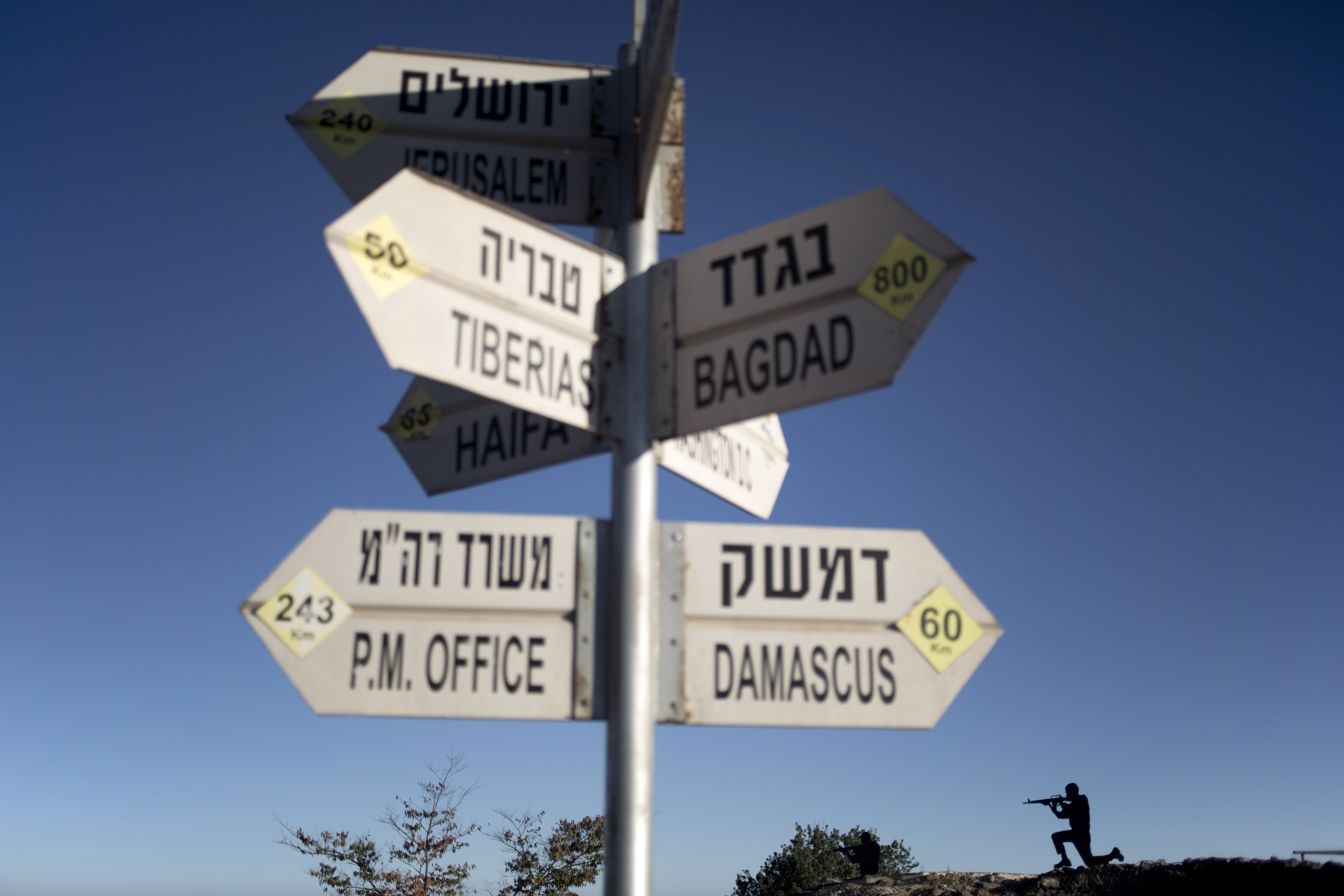 A sign showing the direction and distance to cities stands as a metal board in the shape of a gunman is placed on an old bunker at an observation point on Mt. Bental in the Israeli controlled Golan Heights, overlooking the border with Syria, Thursday, Aug. 28, 2014. (AP Photo/Ariel Schalit) (AP)