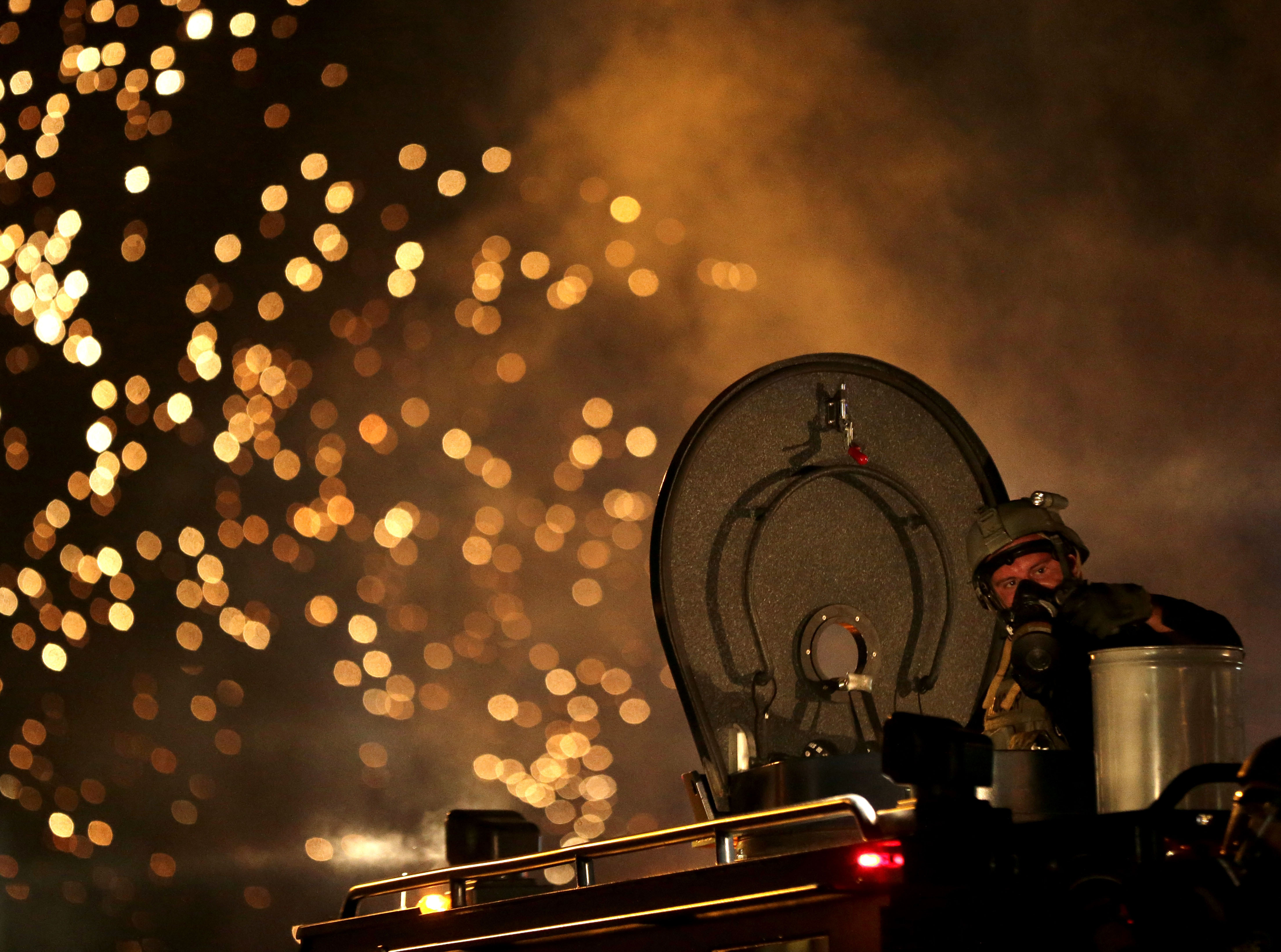 A law enforcement officer on a tactical vehicle watches after a device was fired to disperse a crowd Sunday, Aug. 17, 2014, during a protest for Michael Brown, who was killed by a police officer last Saturday in Ferguson, Mo. As night fell Sunday in Ferguson, another peaceful protest quickly deteriorated after marchers pushed toward one end of a street. Police attempted to push them back by firing tear gas and shouting over a bullhorn that the protest was no longer peaceful. (AP Photo/Charlie Riedel) (AP)
