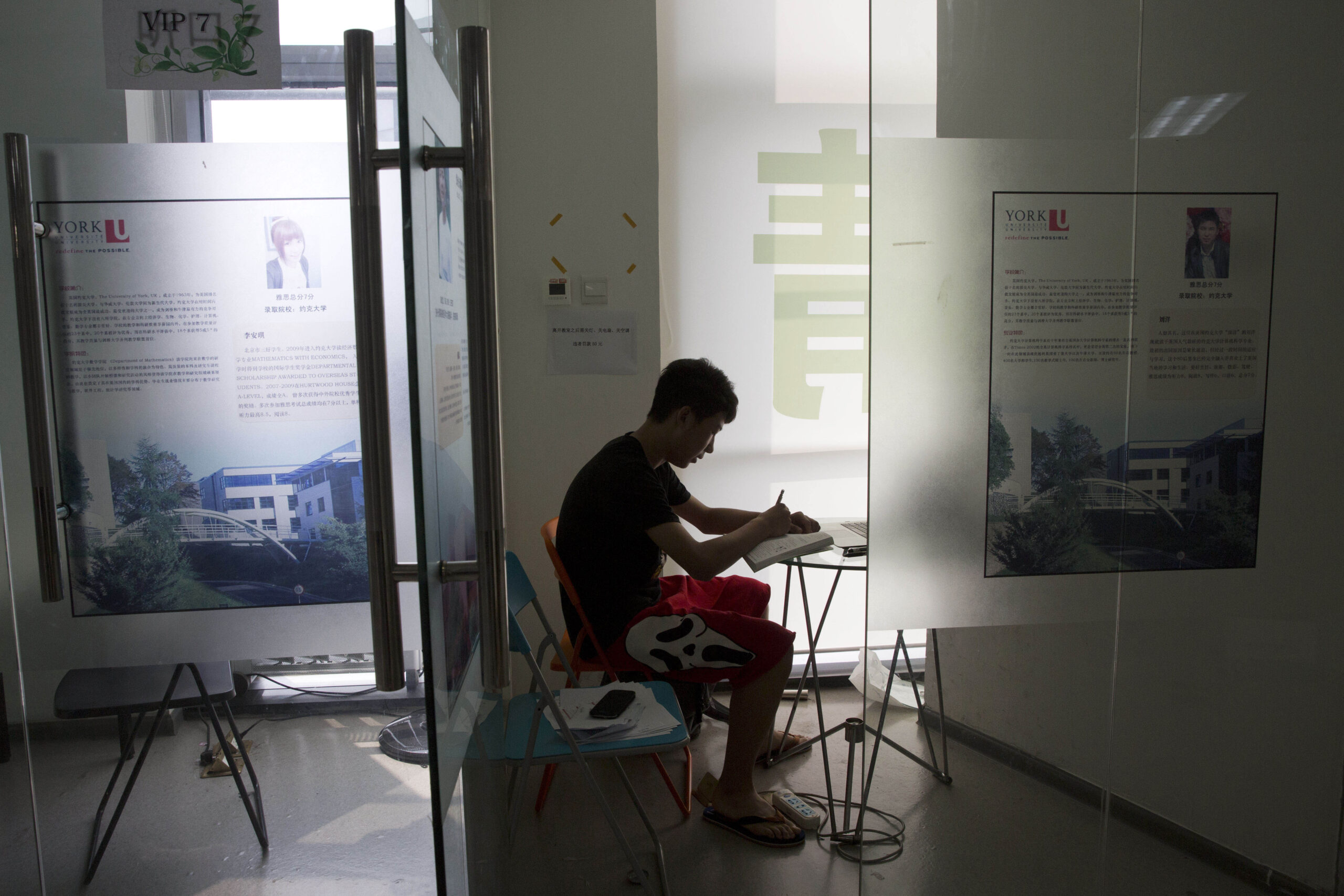 HOLD FOR STORY BACK TO SCHOOL CHINA HIGH SCHOOL IN AMERICA In this photo taken Thursday, June 26, 2014, 16-year-old Zhang Kaisheng studies near advertisements for oversea schools at Focus Education, a tutoring and consulting agency in Beijing, China. Like a growing number of Chinese teenagers, Zhang plans to enroll this fall in a private U.S. high school where he and his parents hope he will get a more well-rounded _ if far more expensive _ education. Tuition, room and board can cost around $40,000 _ three to four times more than an elite private school in China. (AP Photo/Ng Han Guan) (Ng Han Guan)