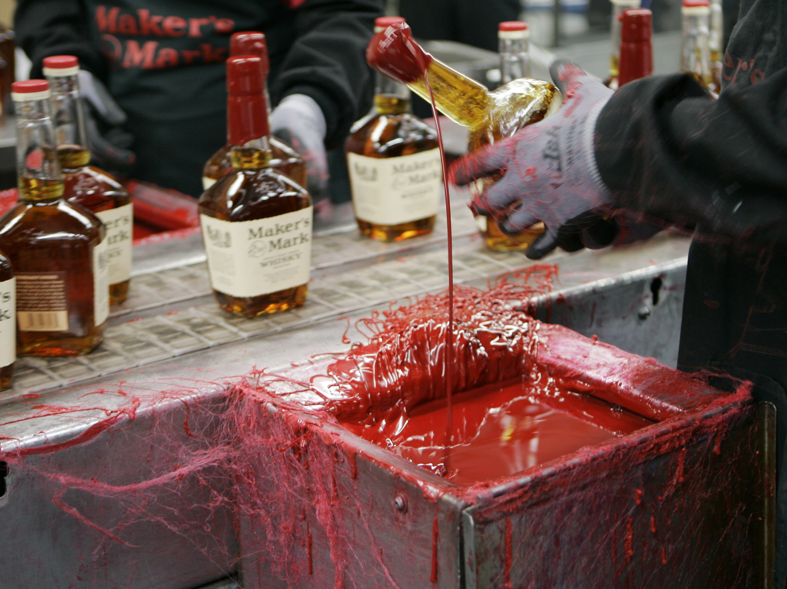 FILE - In this Wednesday, April 8, 2009, file photo, a bottle of Maker's Mark bourbon is dipped in red wax during a tour of the distillery in Loretto, Ky. Kentucky bourbon makers have stashed away their largest stockpiles in more than a generation due to resurgent demand for the venerable brown spirit. (AP Photo/Ed Reinke, File) (AP)