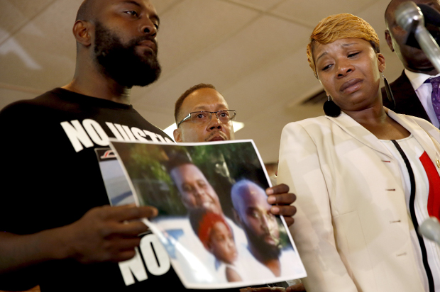 Lesley McSpadden, right, the mother of Michael Brown, watches as Brown's father, Michael Brown Sr., holds up a family picture, Aug. 11, 2014, in Ferguson, Mo. (AP/Jeff Roberson)