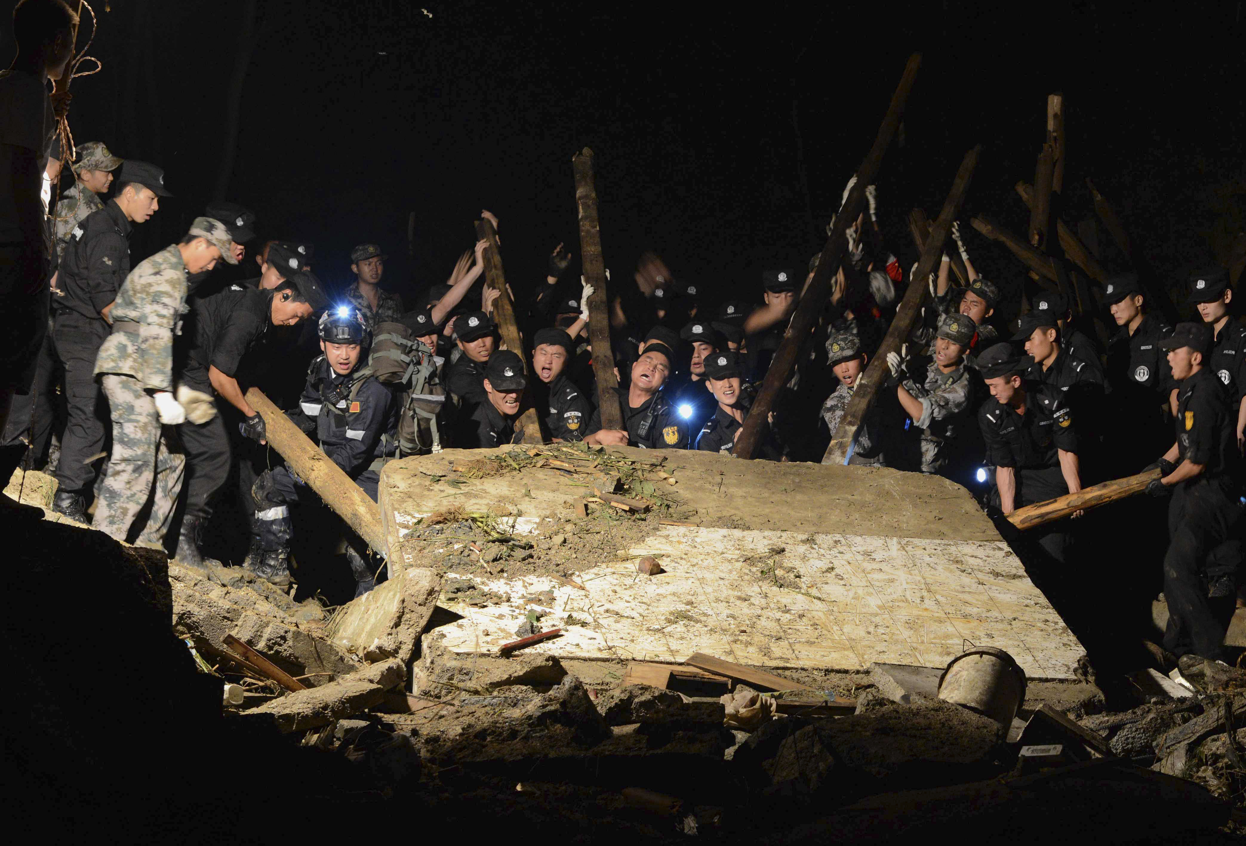 Rescue workers lift a wall that collapsed after a landslide hit Yingping village in Fuquan city in southwest China's Guizhou province Thursday Aug. 28, 2014.   Six people died and 21 remained missing Thursday after a landslide hit a village in southwestern China, according to Chinese state media. (AP Photo) CHINA OUT (AP)