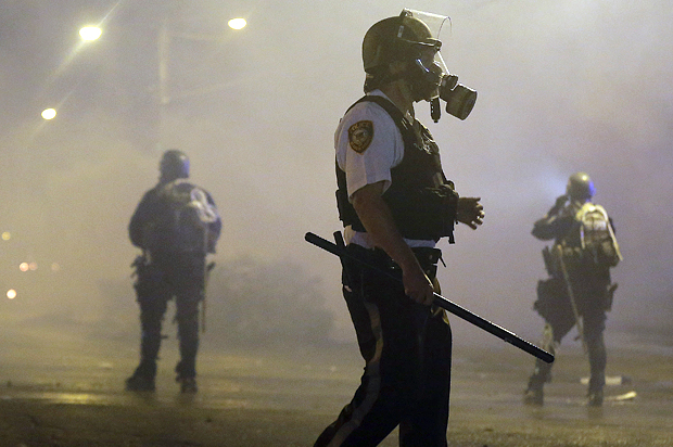 Law enforcement officers wait to advance Sunday, Aug. 17, 2014, after firing tear gas to disperse a crowd in Ferguson, Mo. (AP/Charlie Riedel)