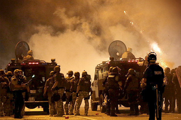 Police wait to advance after tear gas was used to disperse a crowd, Aug. 17, 2014, in Ferguson, Mo. (AP/Charlie Riedel)